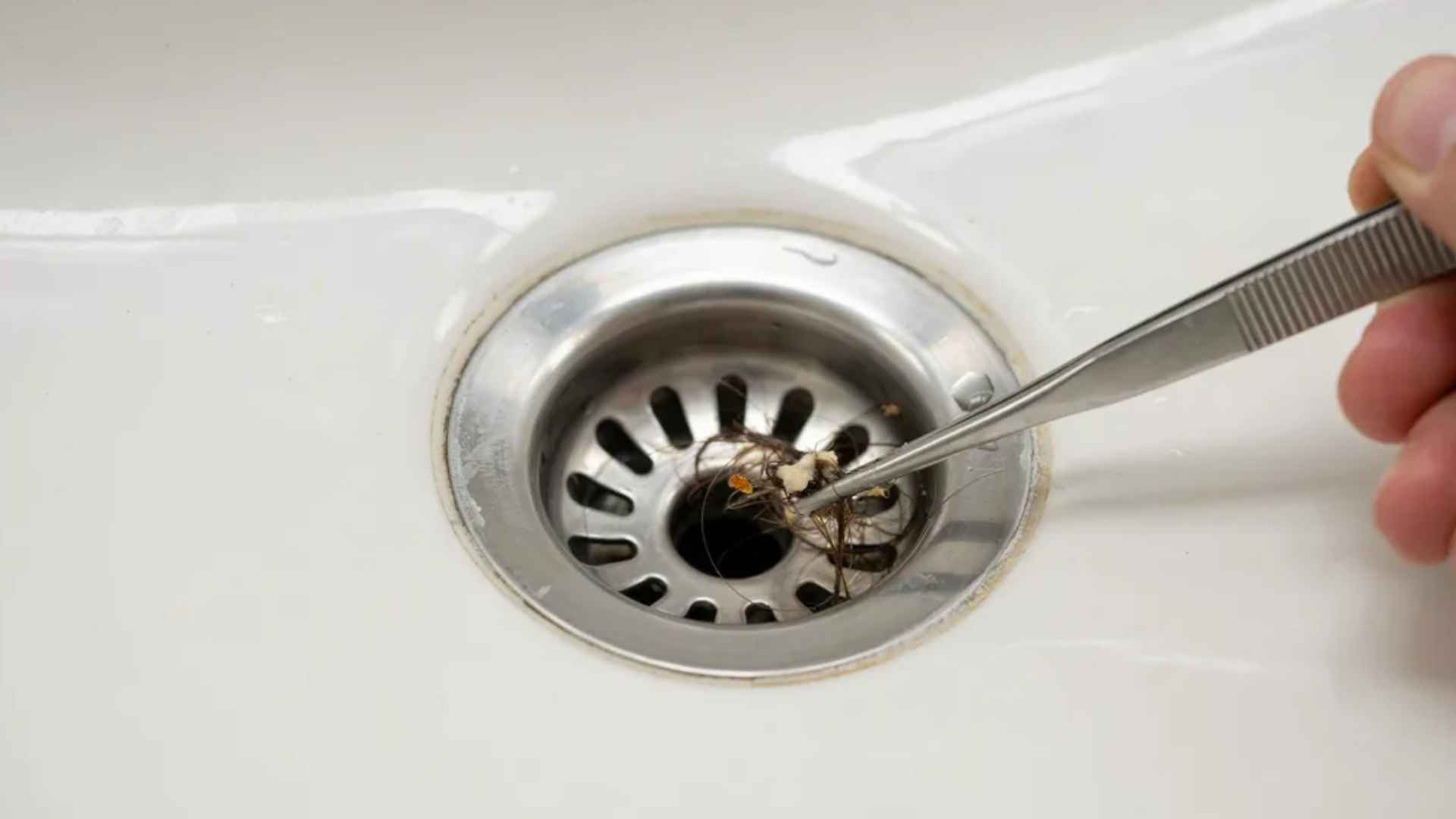 Removing hair and debris from a sink drain before testing water flow