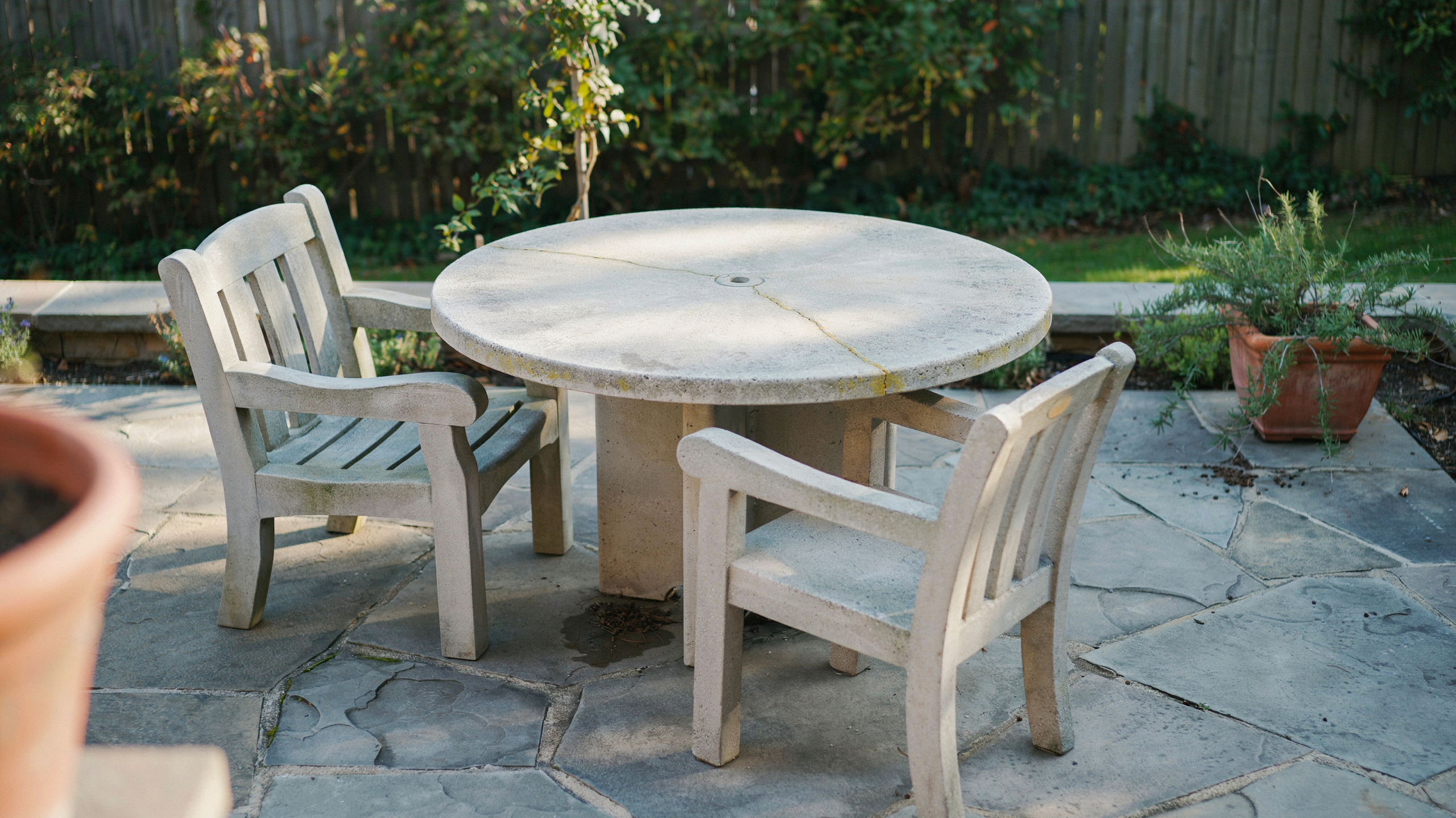 Concrete and stone patio furniture on a backyard patio, naturally arranged, no people.