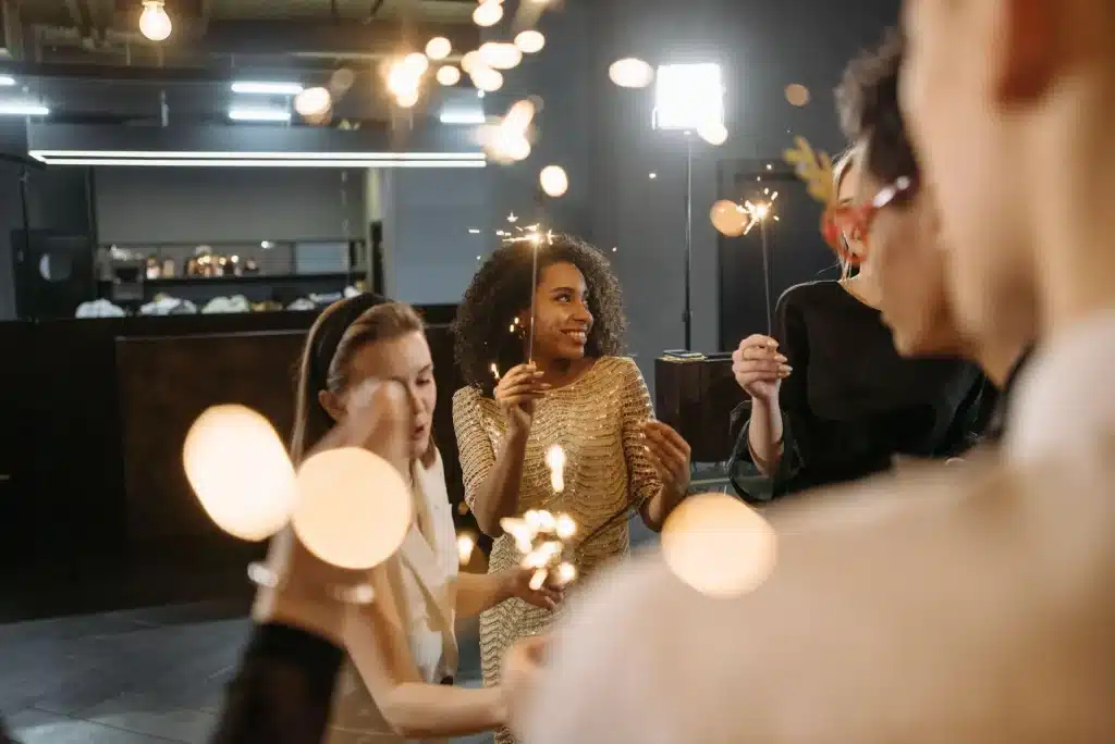 Group of people holding sparklers in a dimly lit indoor setting