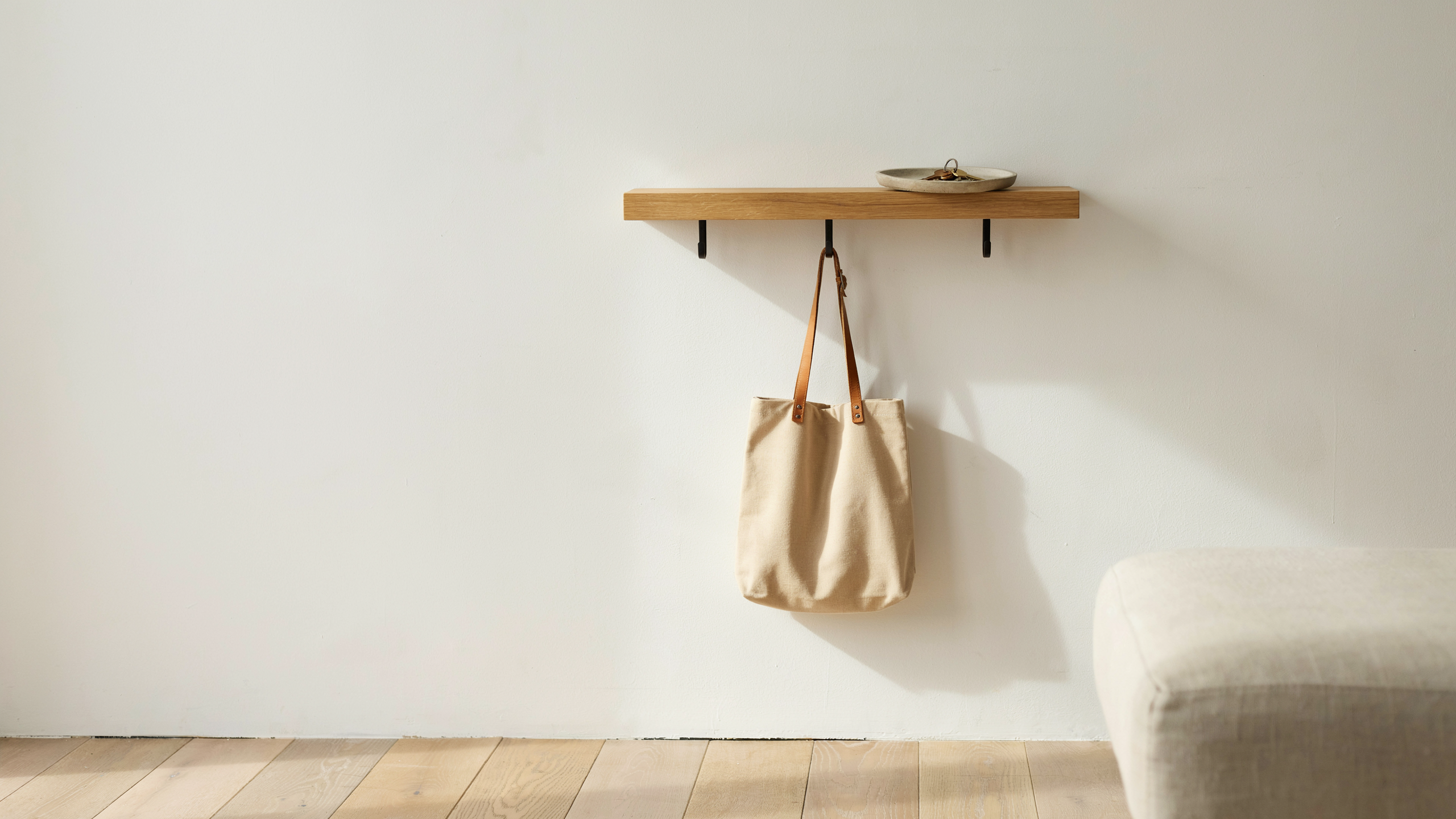 Entry wall with hooks and small shelf used as drop zone for bag and keys, keeping belongings organized and preventing clutter near bedroom entrance.
