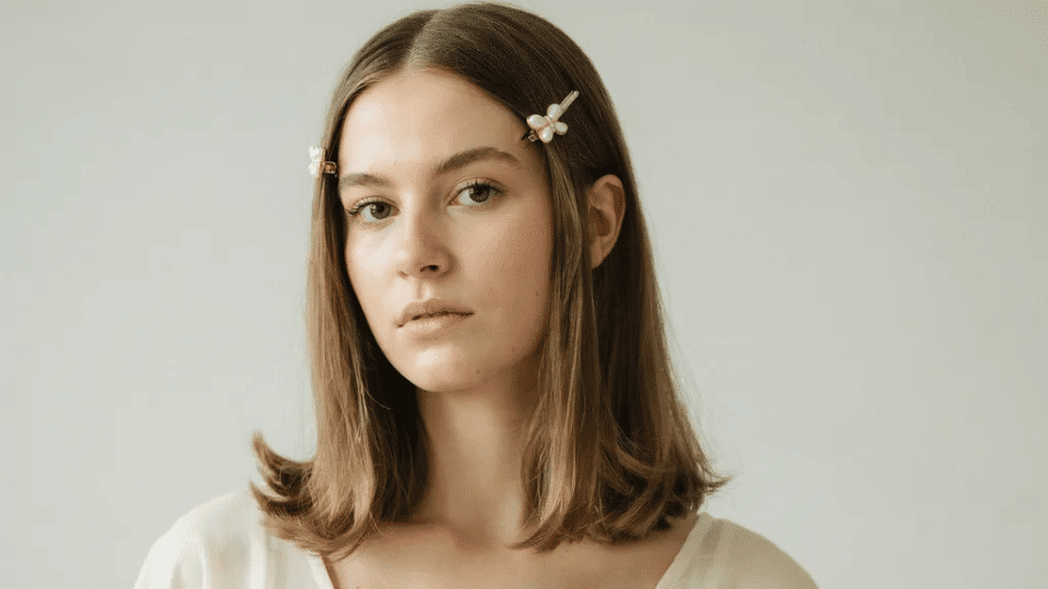 Straight hair with flipped outward ends and small side clips, classic Y2K inspired early 2000s hairstyle