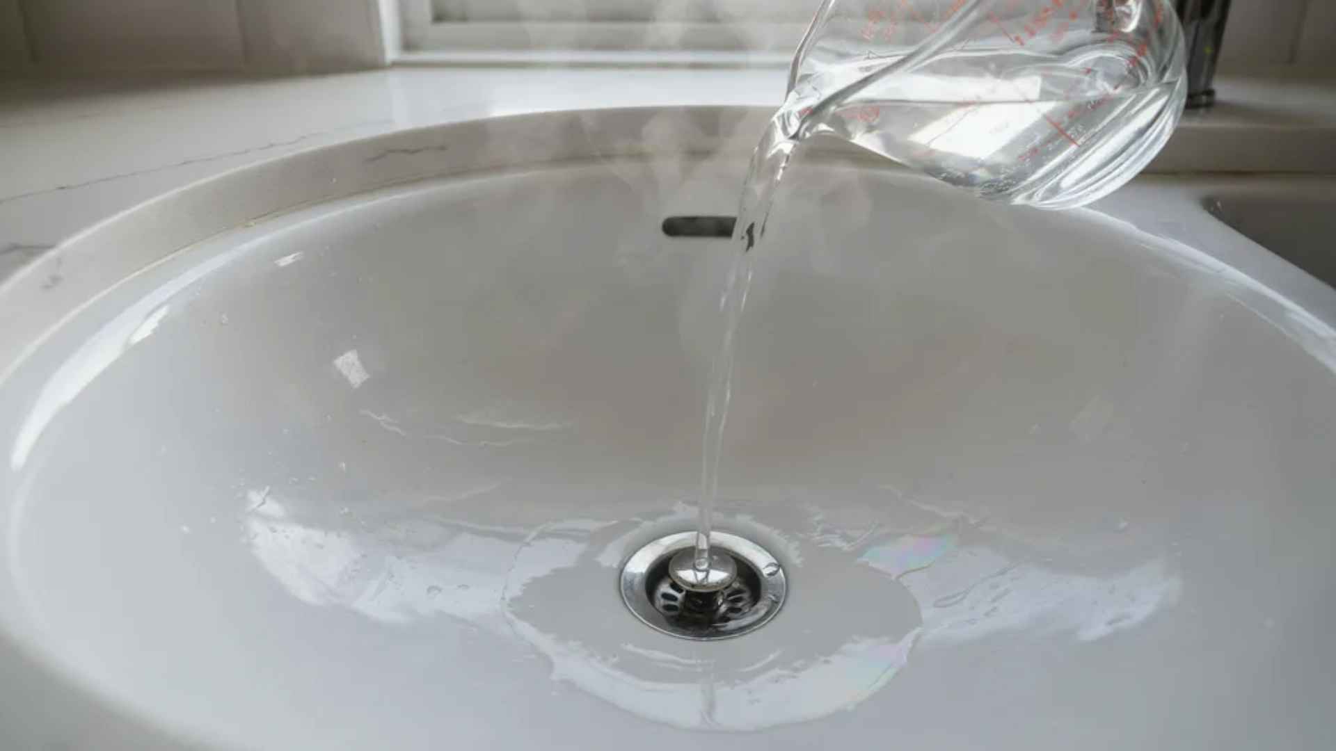 Hot water poured into a clean sink drain to loosen soap and grease buildup