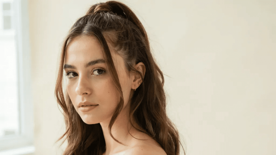 Half-up mini ponytail with soft face tendrils on medium long hair, clean natural Y2K inspired hairstyle look