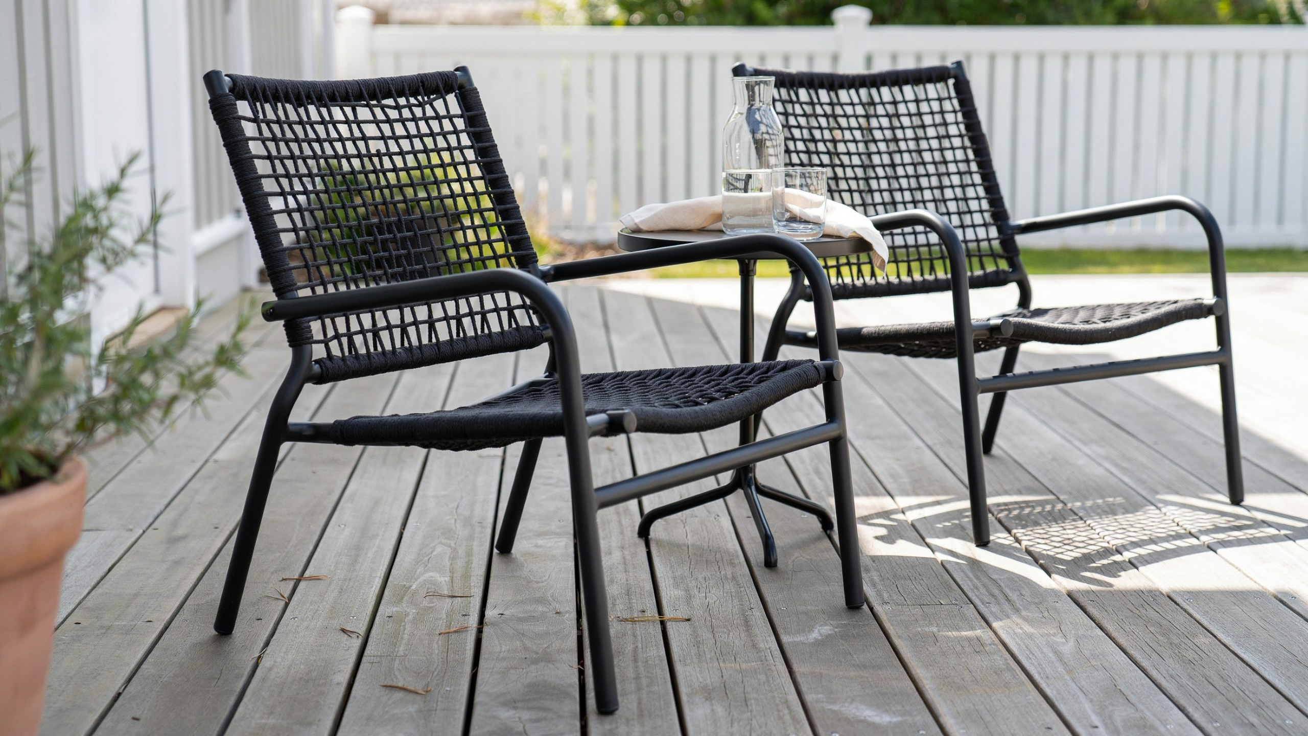 Mesh and sling patio chairs realistically arranged on a sunlit deck.