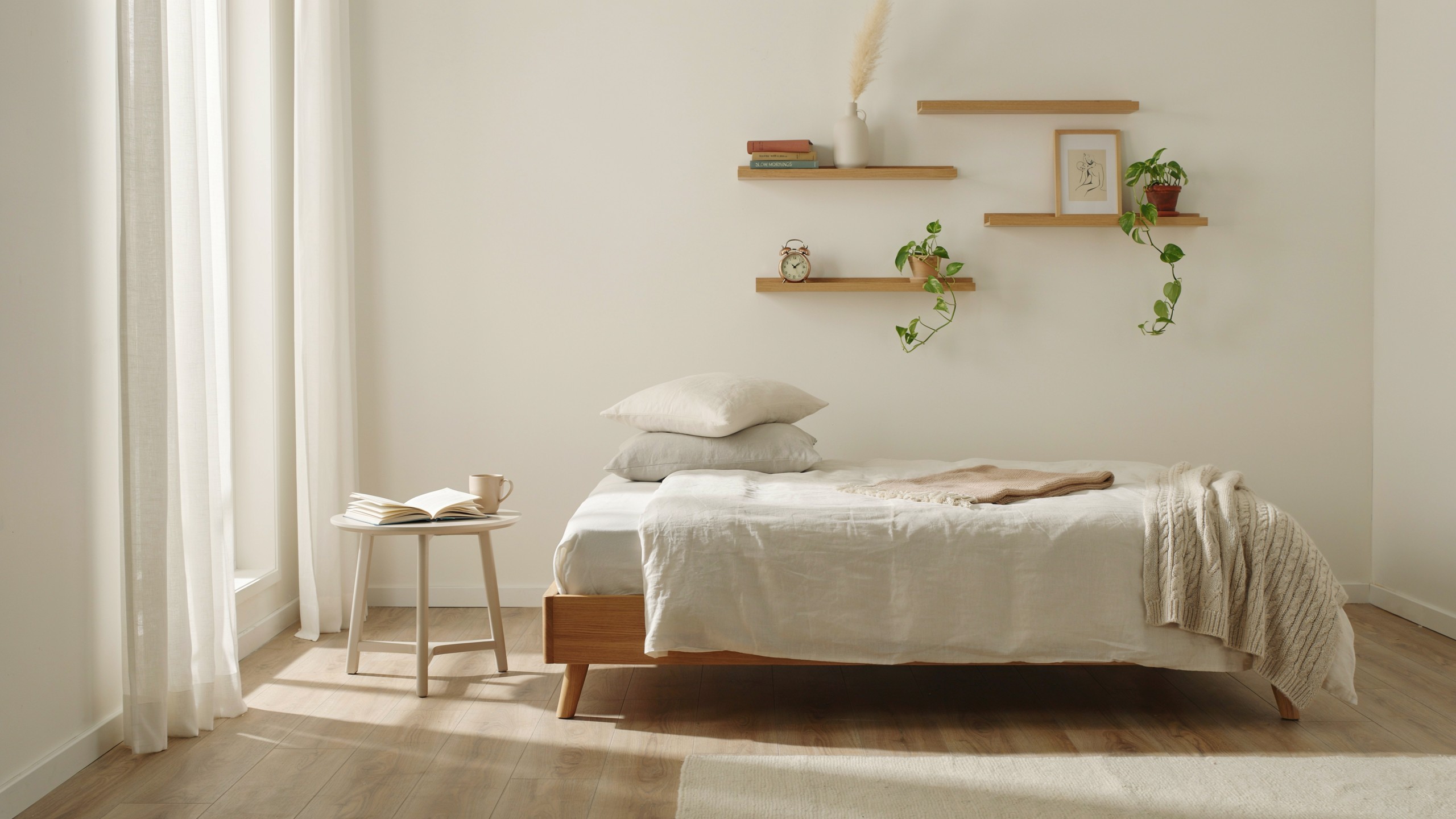Minimalist bedroom with floating wall shelves holding books and decor, bright and uncluttered.