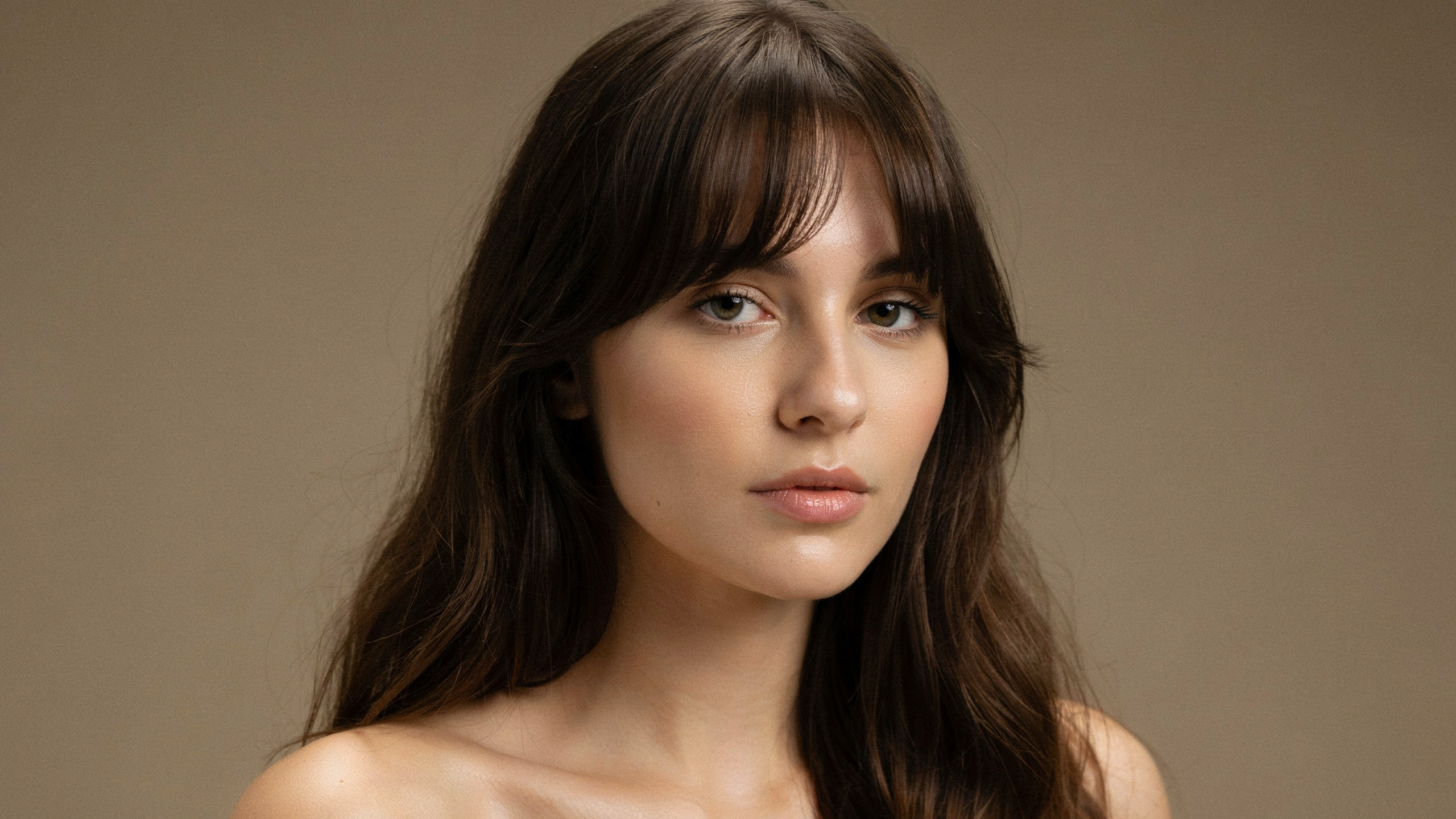 Crescent fringe haircut curving gently downward at the center and lifting at the sides with long layered hair