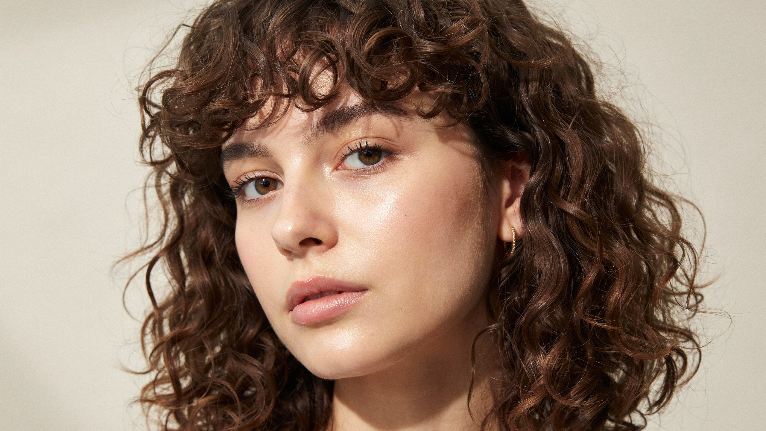 Curly fringe haircut using natural curl pattern to create textured shape and volume across the forehead