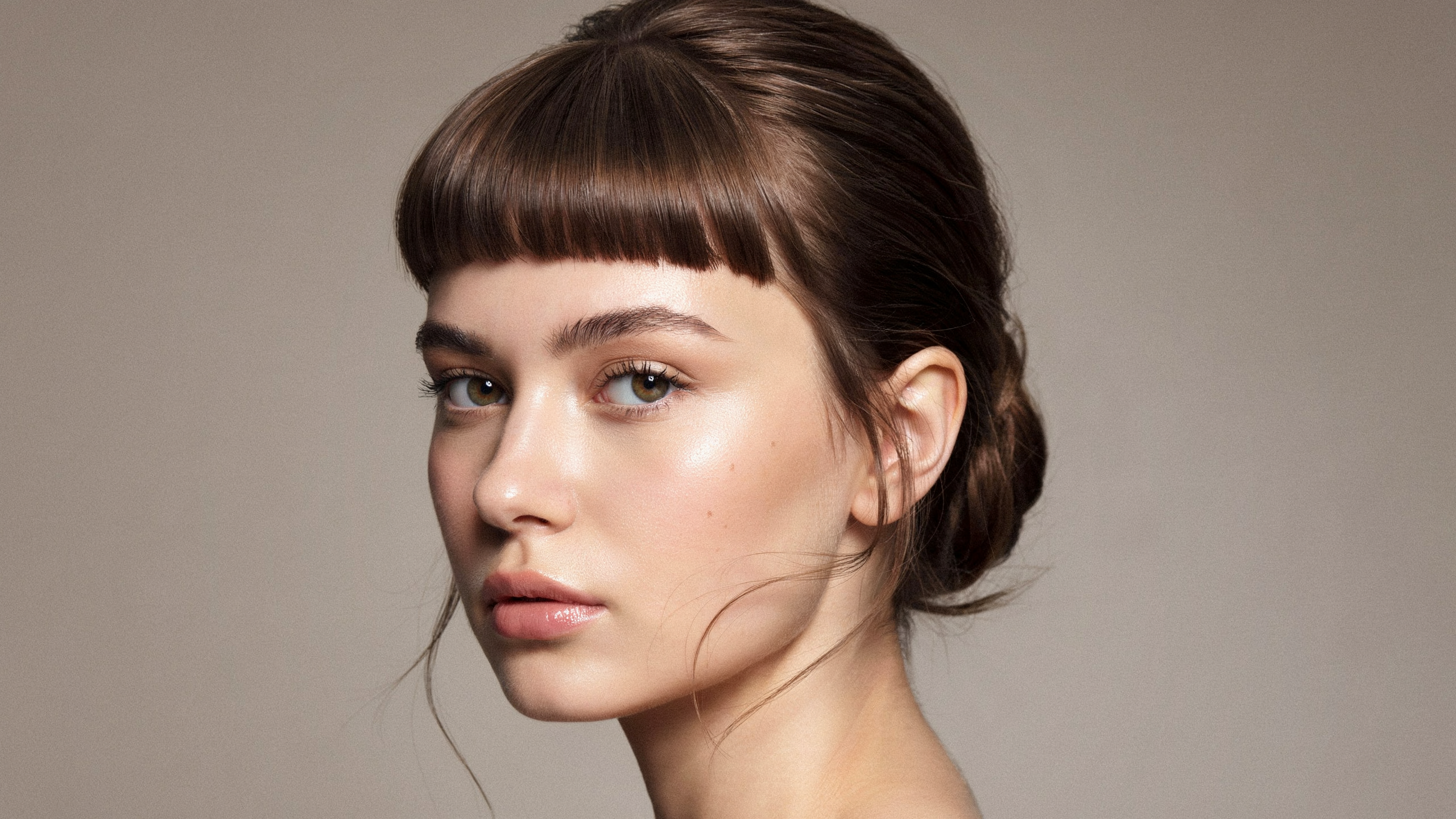 Micro fringe haircut sitting well above the eyebrows on a model with hair styled in an updo