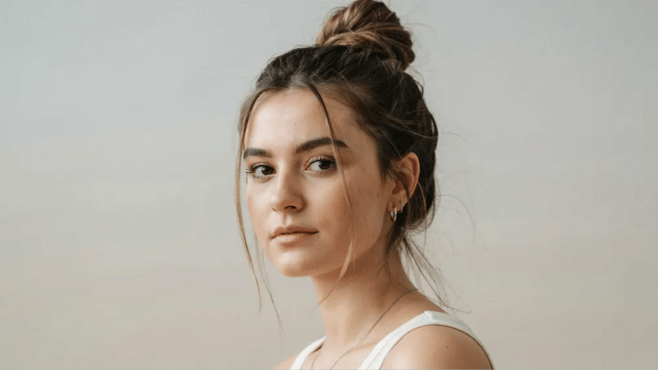 High messy bun with loose face framing strands, edgy Y2K hairstyle with relaxed undone early 2000s look