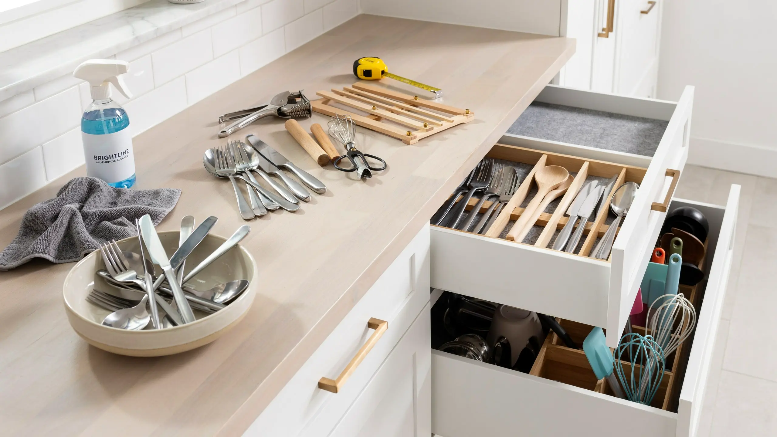 Open kitchen drawer showing neatly organized utensils and wooden knife tray with various tools.