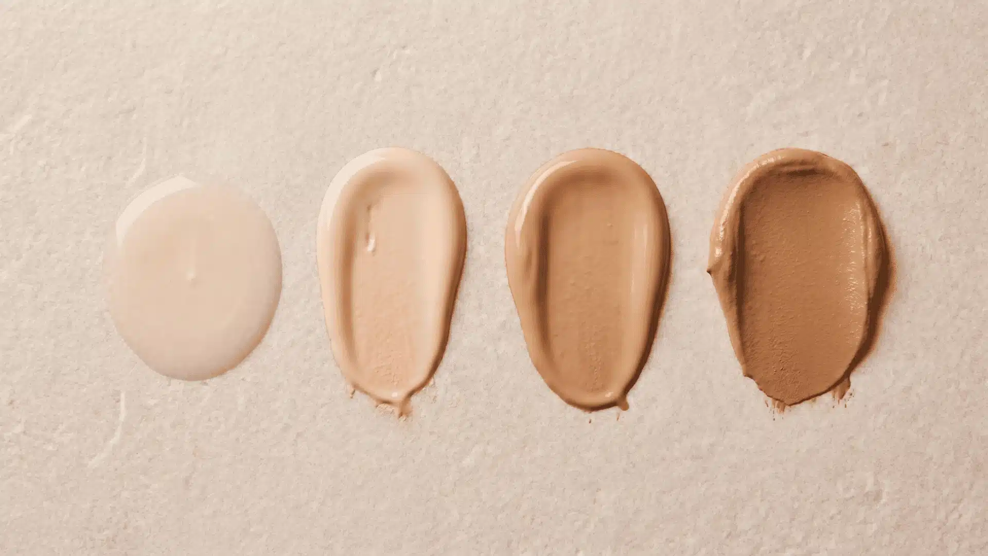 Smooth foundation swatches showing coverage levels on a neutral surface under soft lighting.