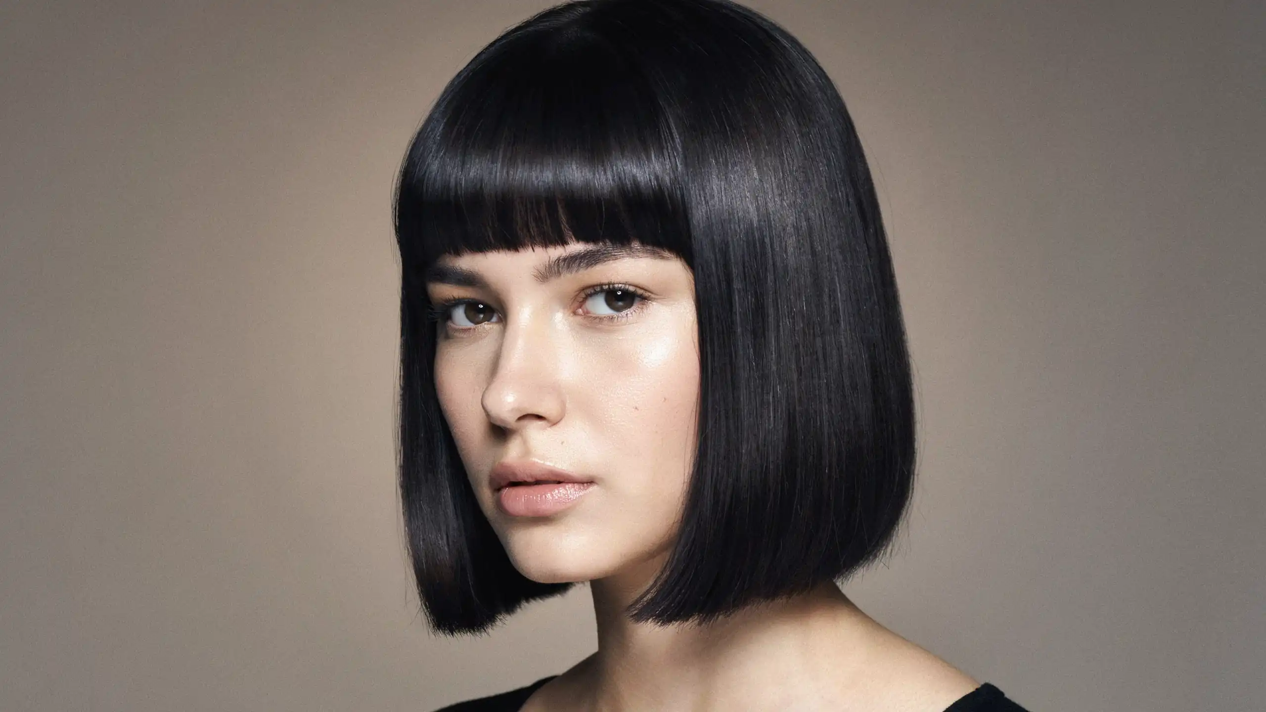 Blunt fringe haircut with a straight even line across the forehead on a model with thick straight hair.