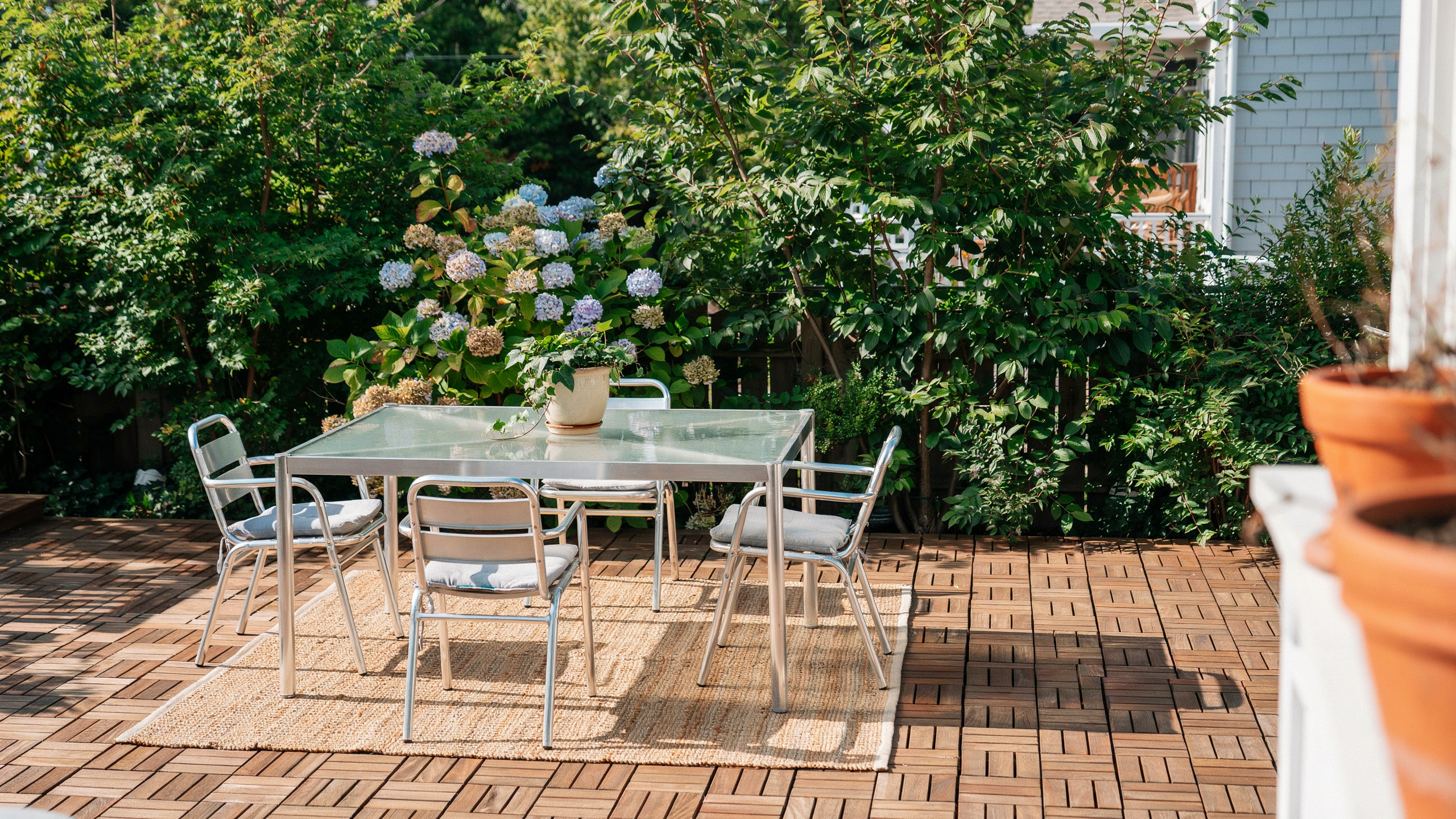 Clean glass patio table outdoors with chairs, sunlight reflecting, no people.