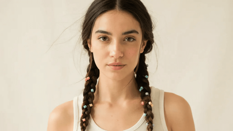 Pigtail braids with colorful beads at ends, playful Y2K party hairstyle with early 2000s nostalgic detail look