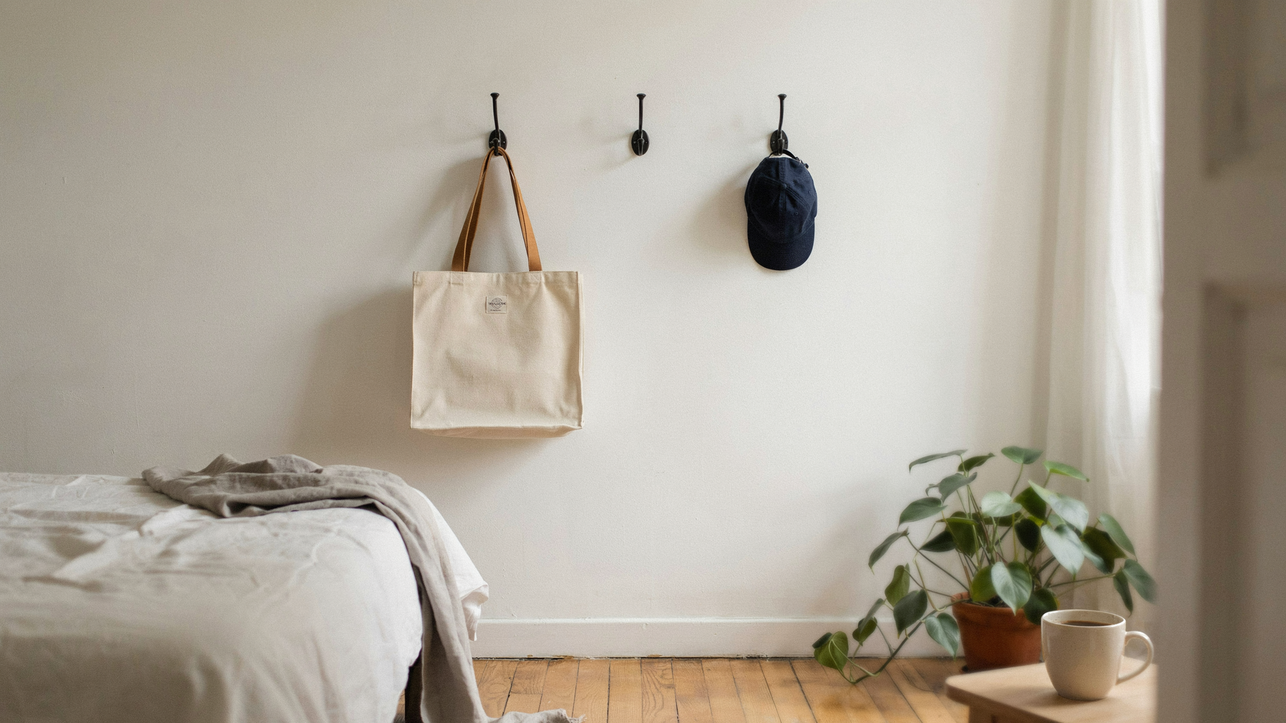 Wall hooks holding bag and hat in a bedroom, minimal and organized.