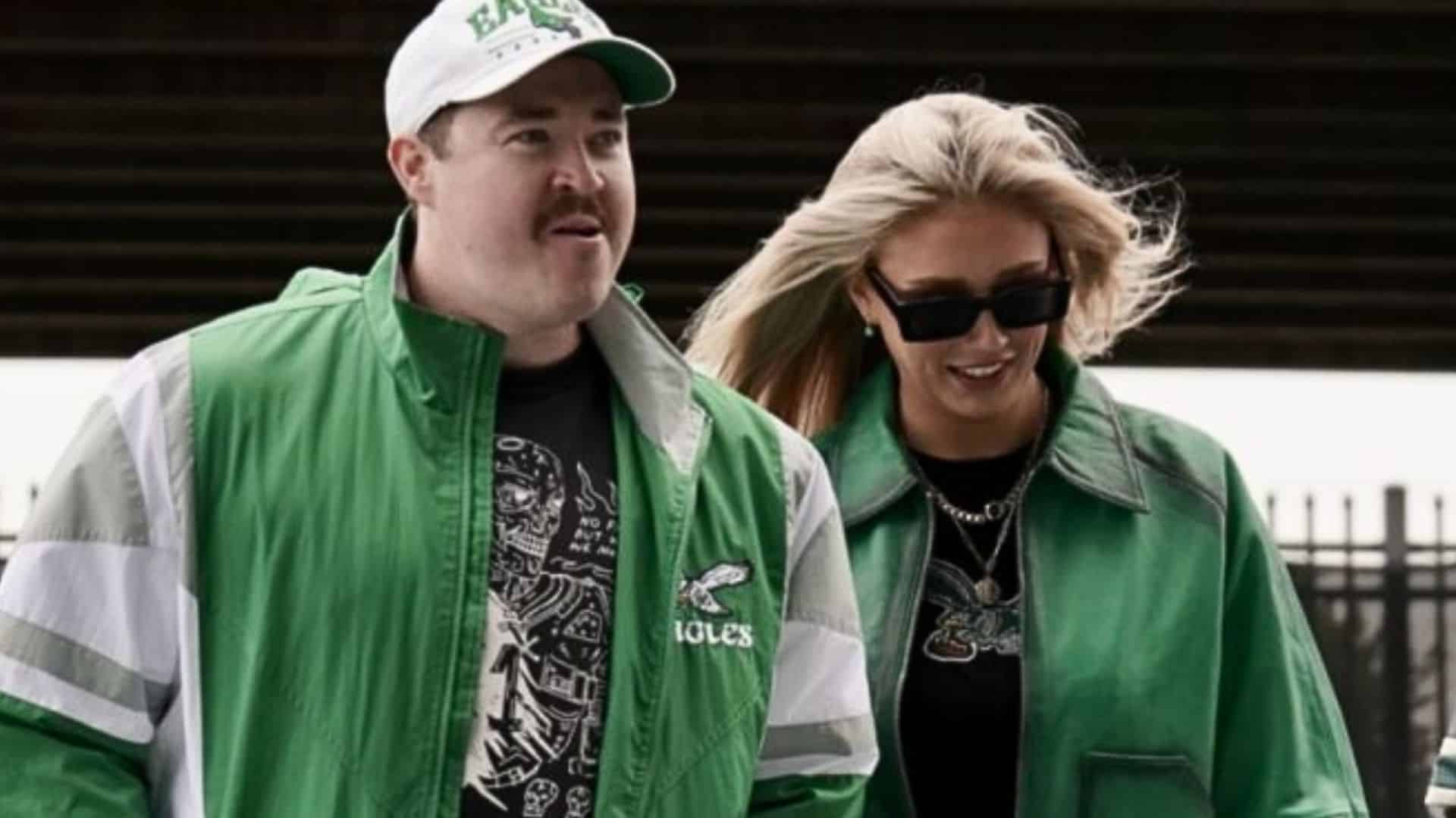 Shane Gillis and Sarah Gillis walking together outdoors in matching green Philadelphia Eagles-inspired outfits