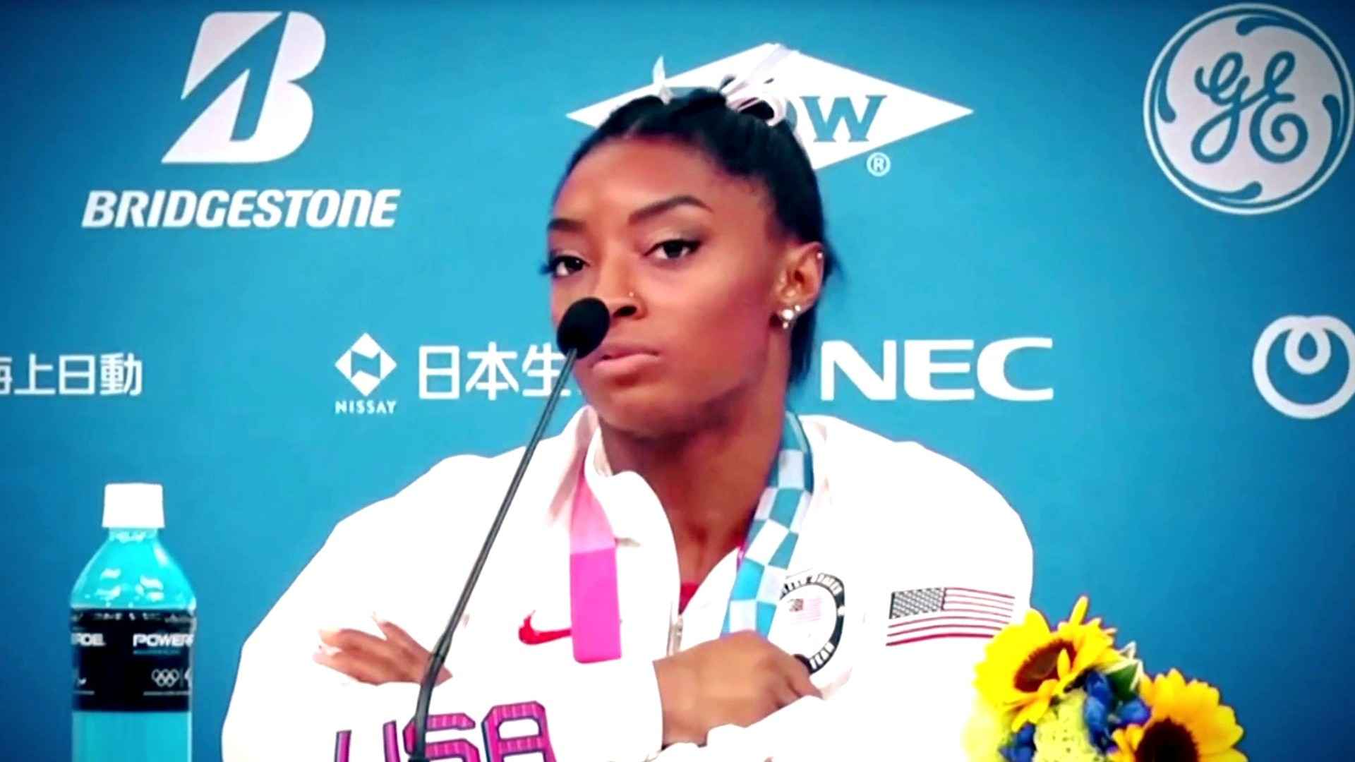 imone Biles at press conference with medal and flowers