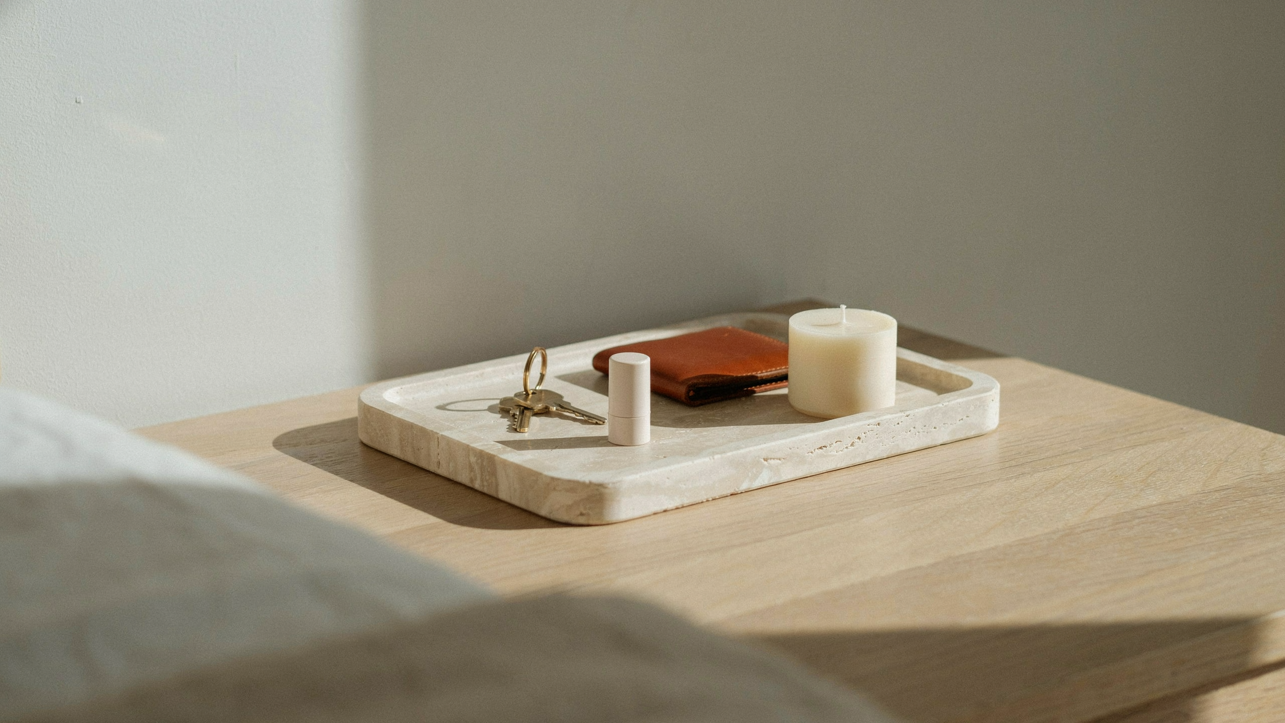 Minimal dresser with a single tray neatly organizing keys, and lip balm, keeping the surface clean and clutter-free in a calm bedroom setting.