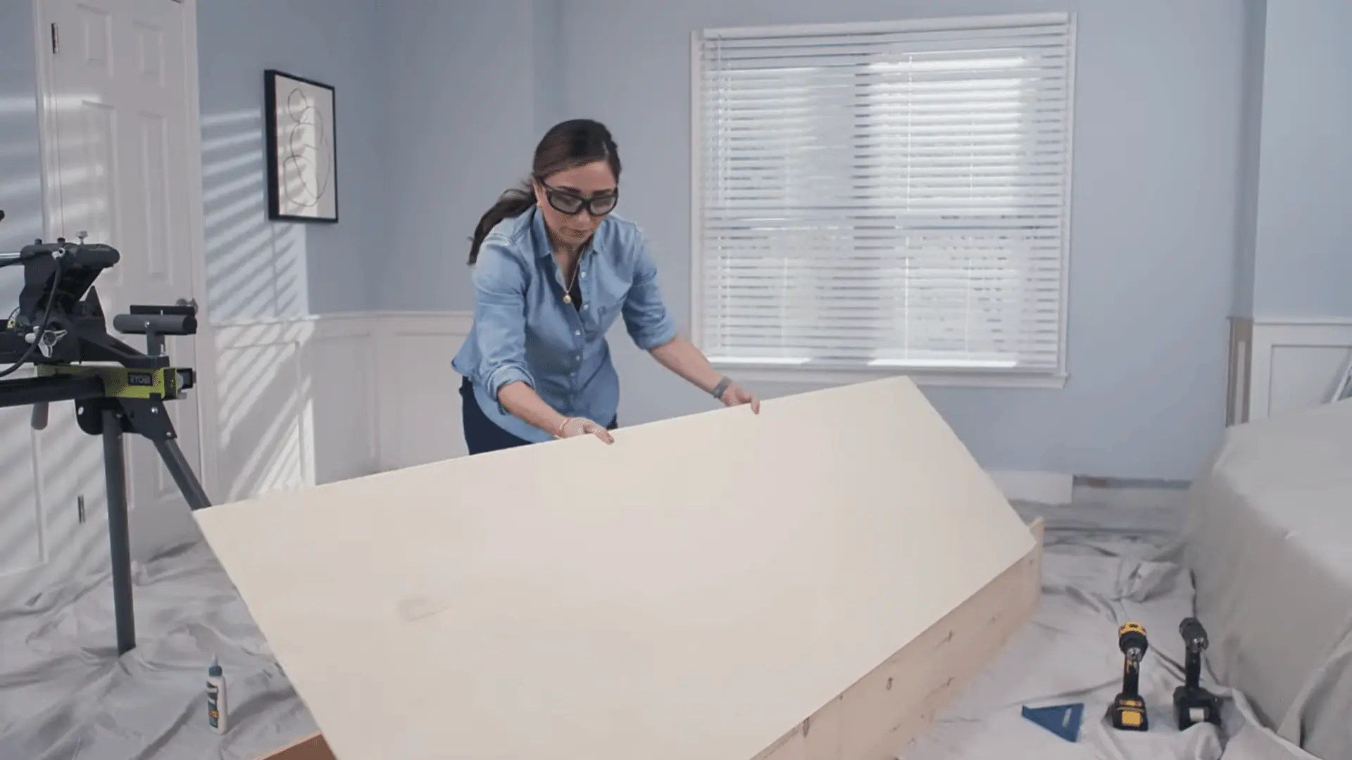 Person assembling a large wooden shelf panel with tools nearby during a DIY woodworking project