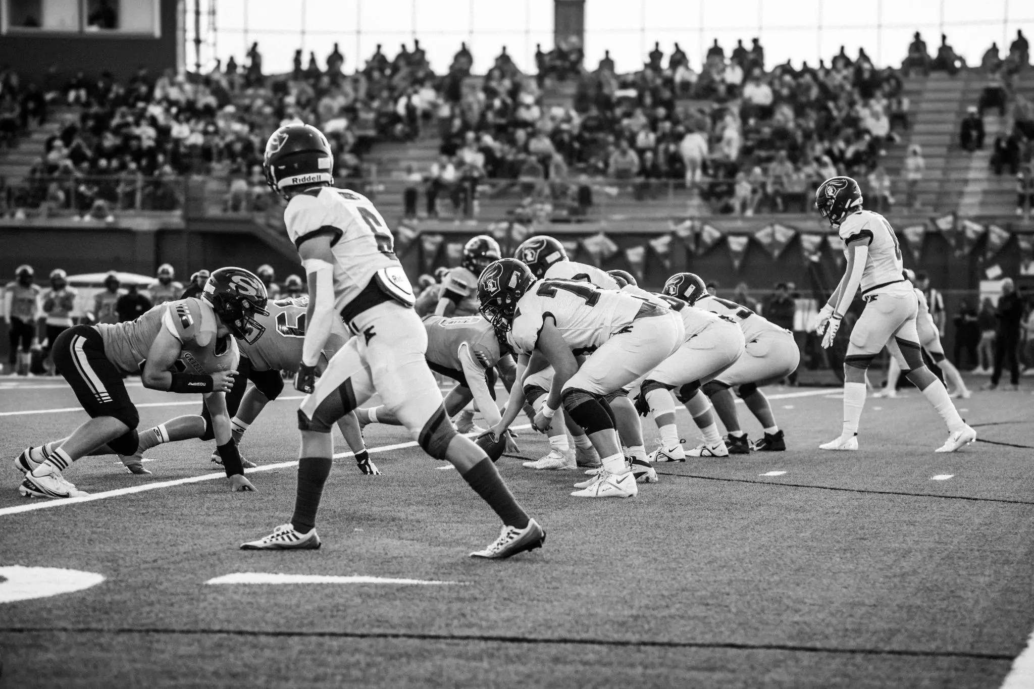 Football players in formation on a field during a game with a crowded stadium background