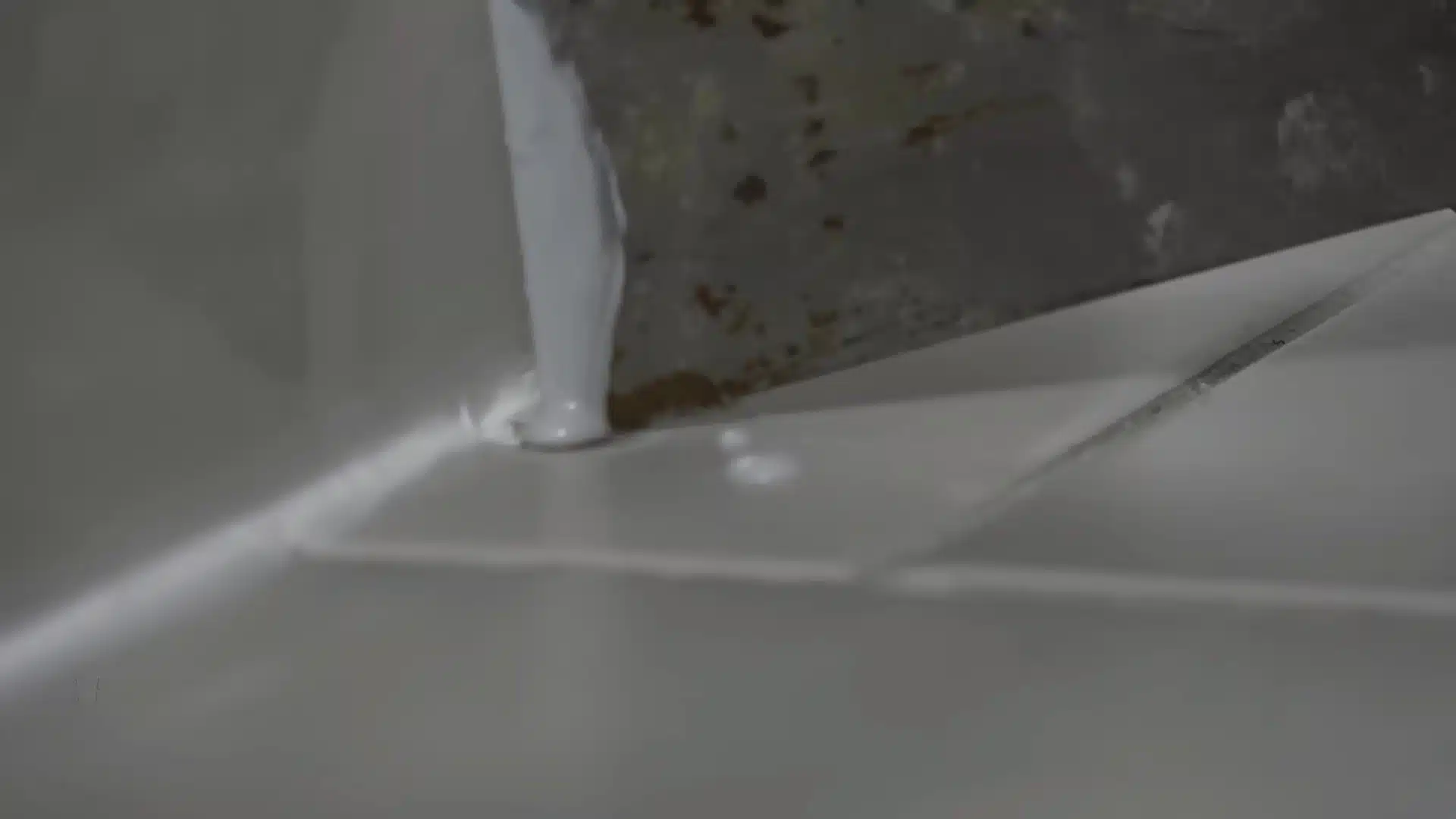 Applying color-matched glaze to a chipped bathroom floor tile with a small brush.