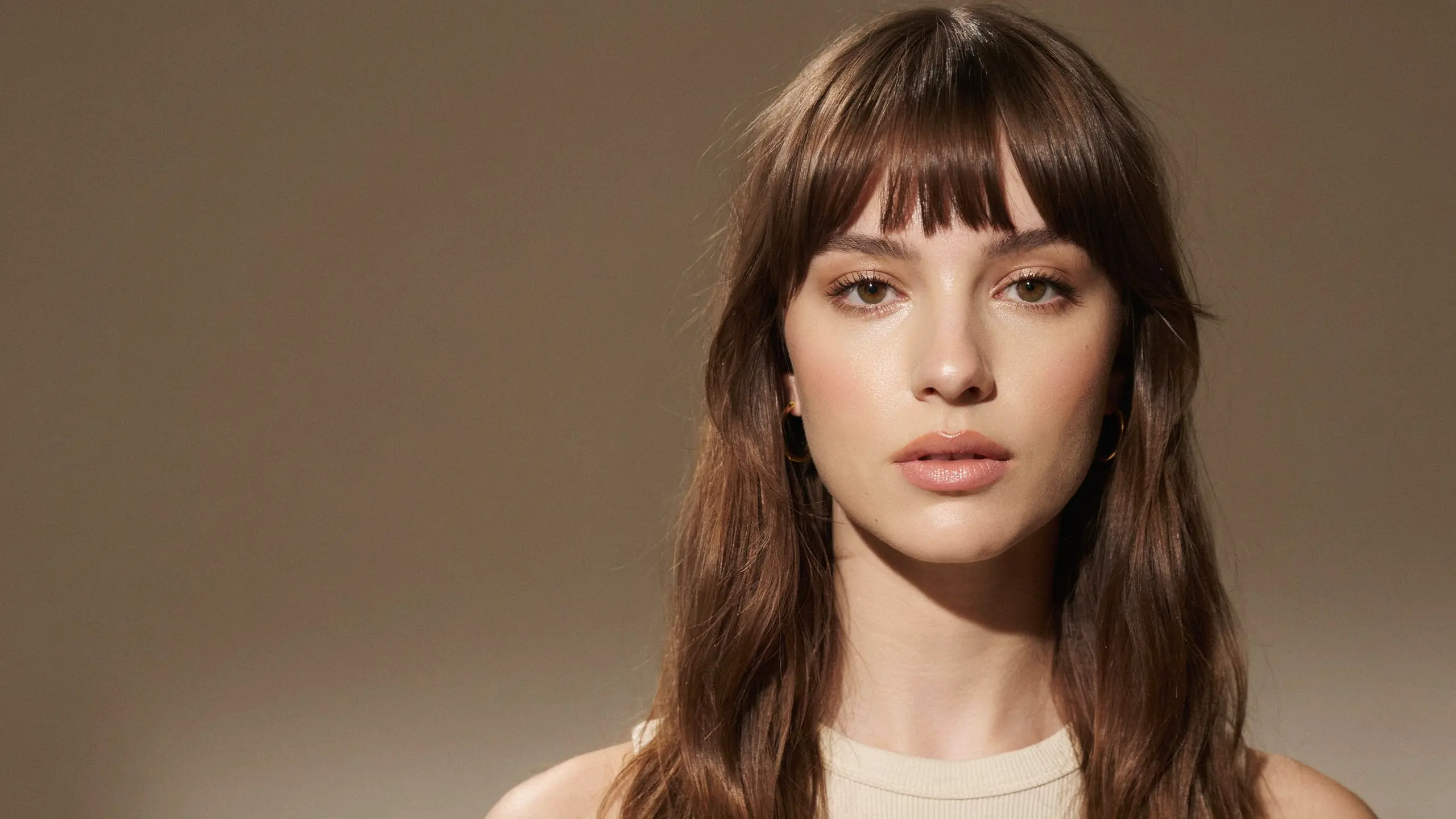 Short baby bangs with a blunt fringe and sleek dark hair for a trendy fashion look