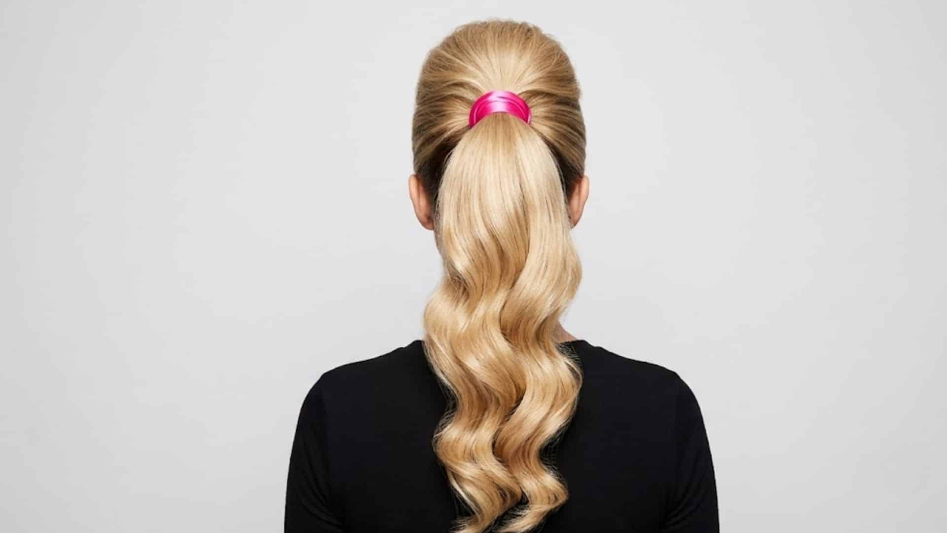 High glossy ponytail with a pink wide glossy tie and voluminous curls