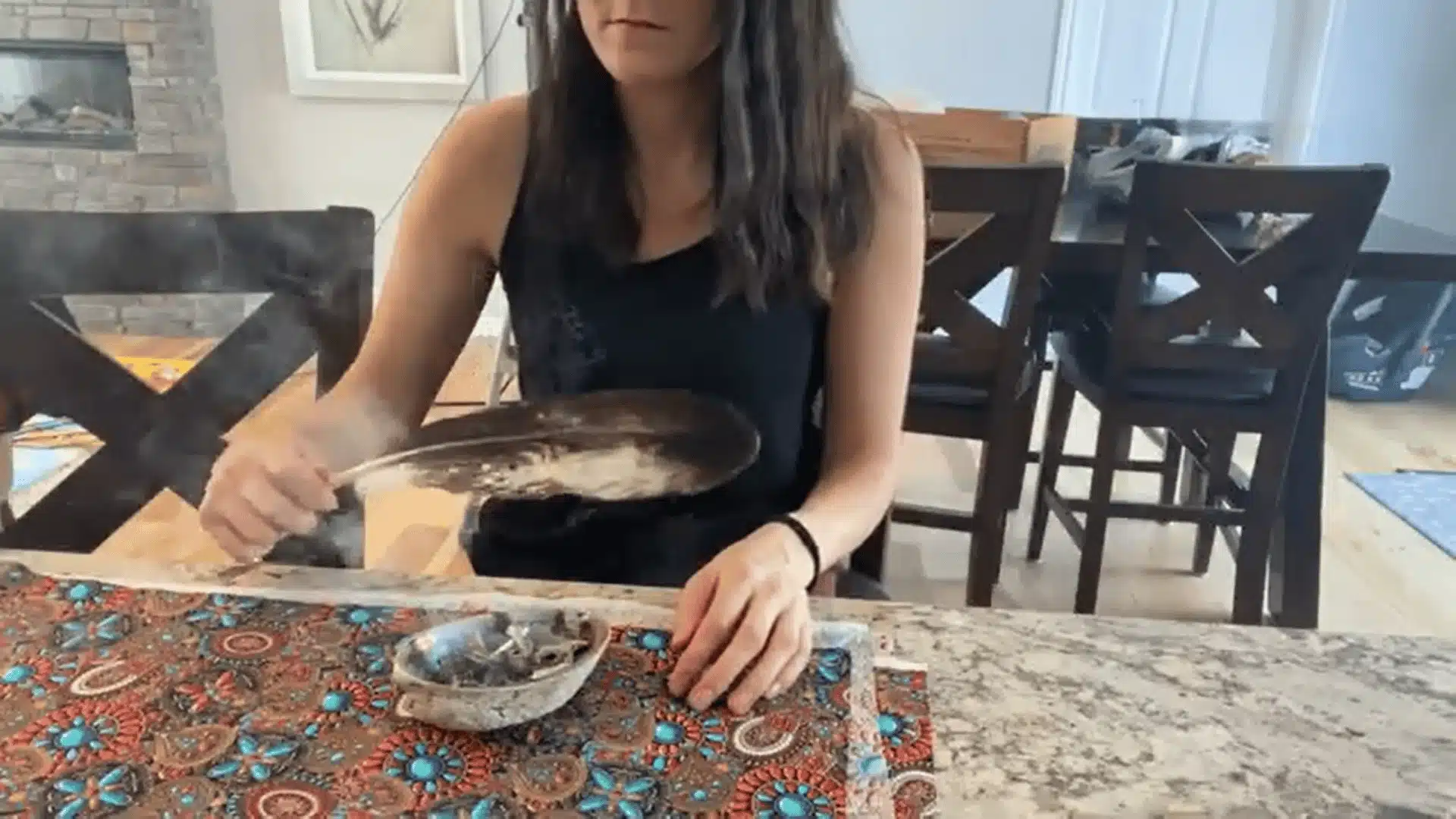 Person using sage smoke to cleanse themselves before home smudging