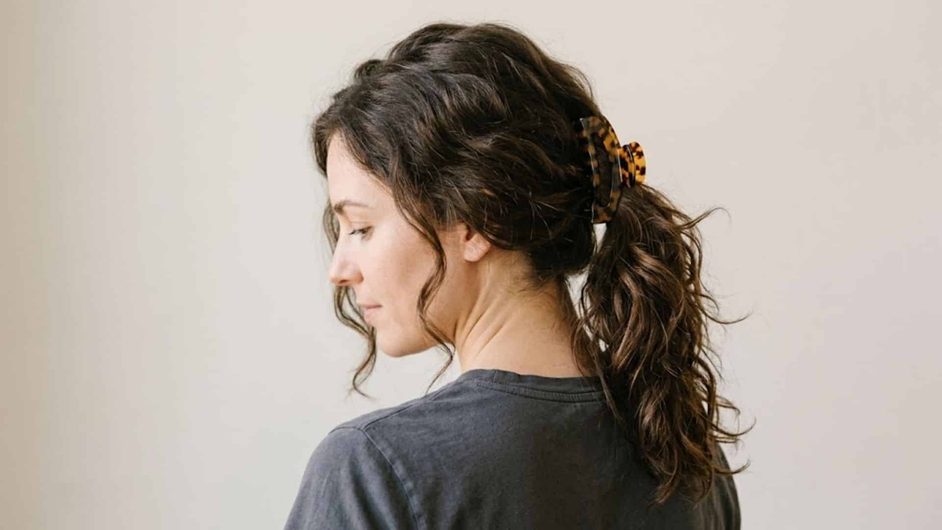 Curly ponytail secured with a claw clip with plain background .