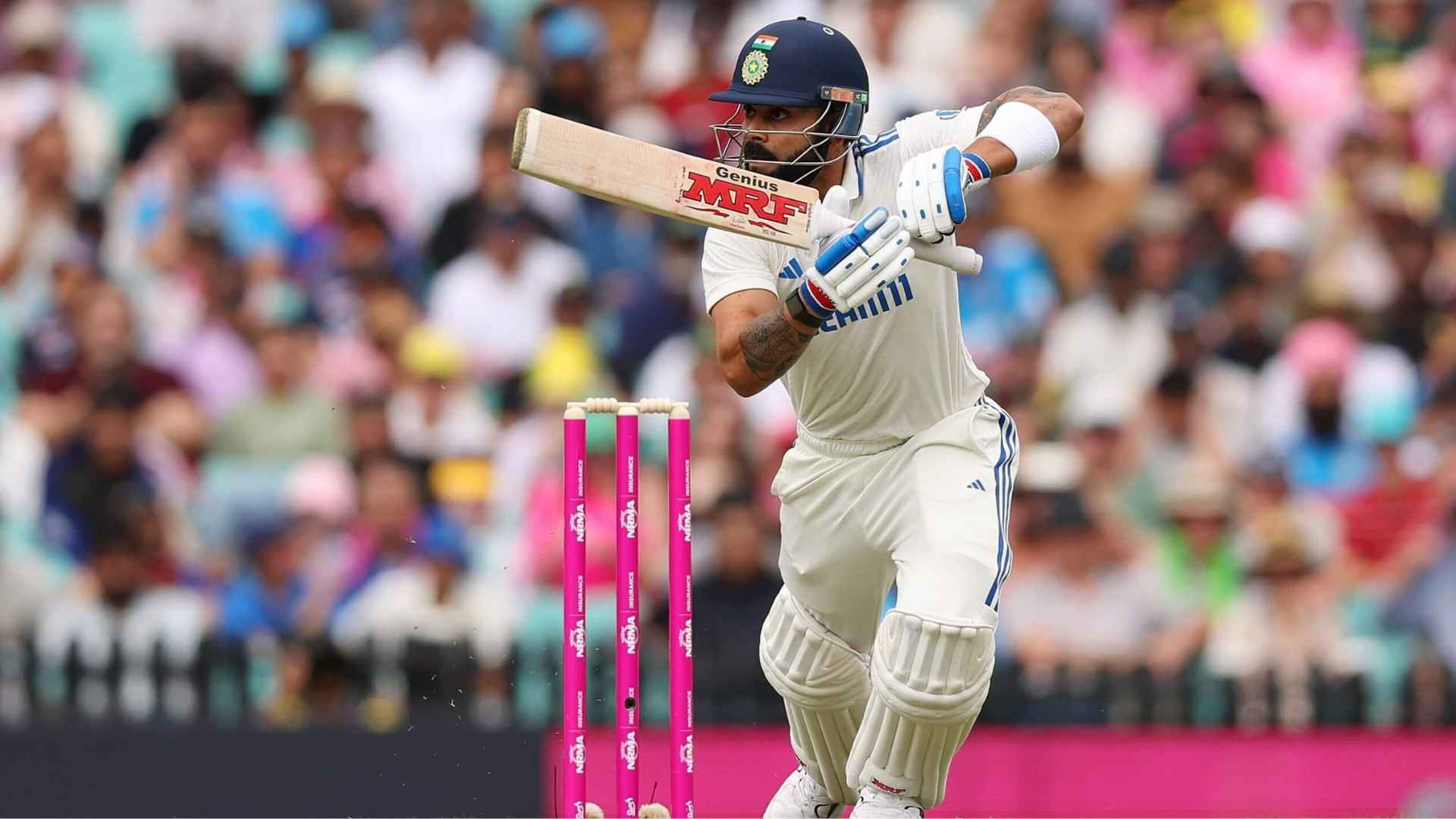 Virat Kohli playing a front-foot shot during a Test cricket match as the crowd watches from the stadium stands.