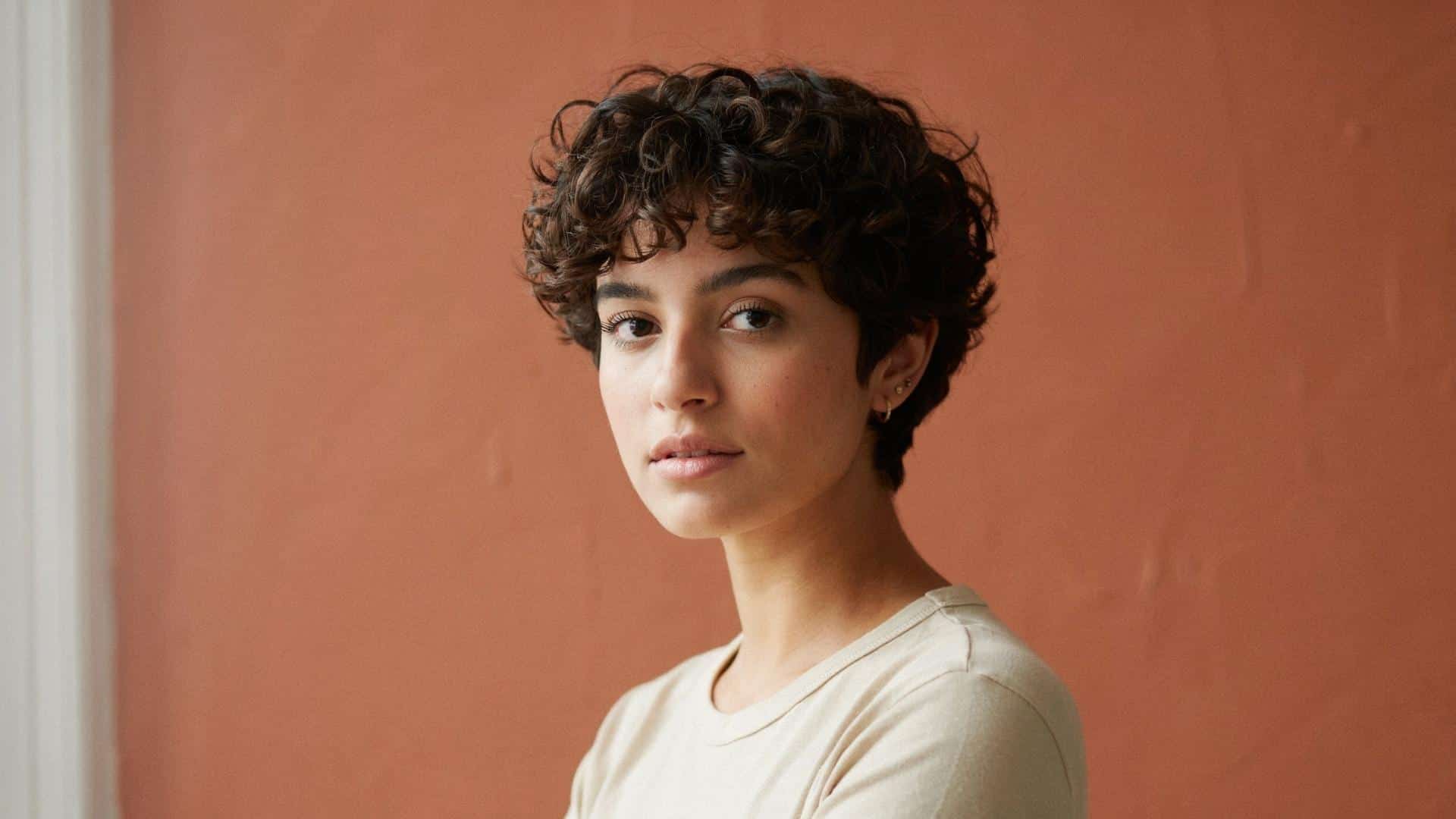 Curly pixie cut with soft ringlets framing the face and short sides.