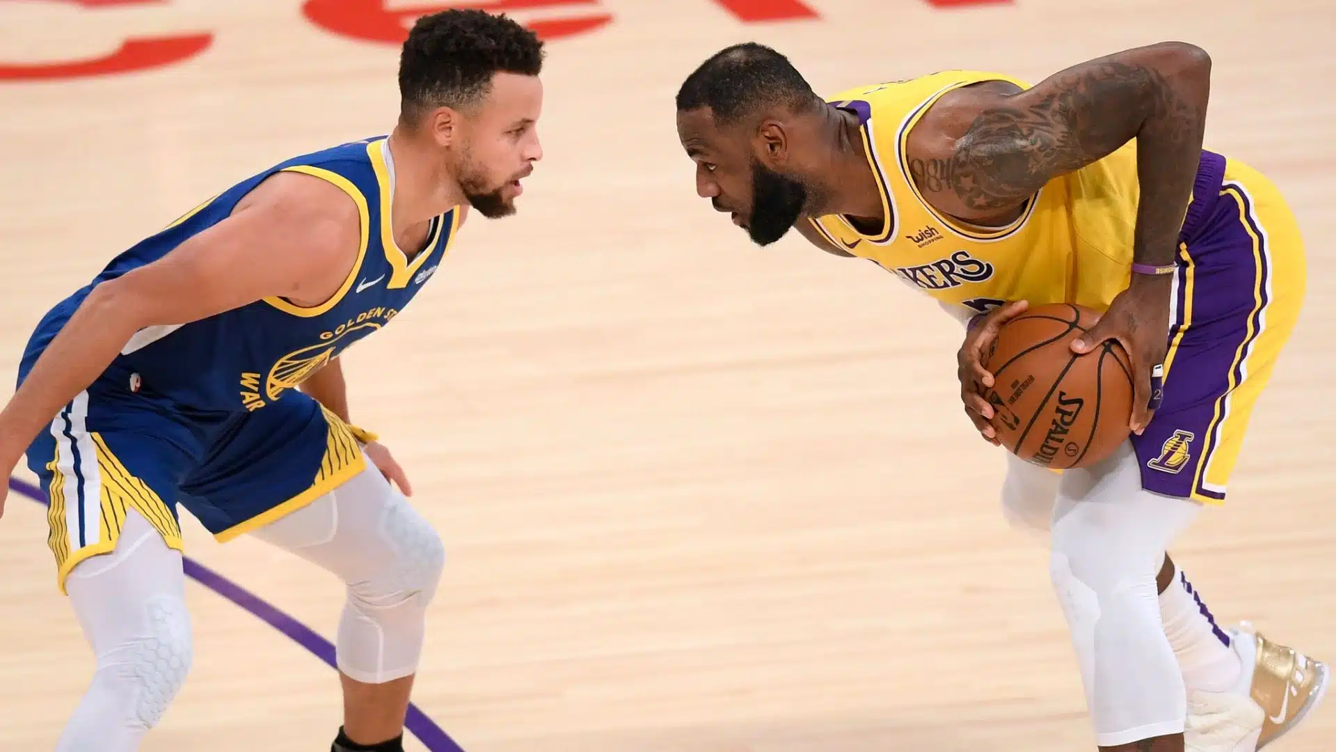 Two basketball players facing each other on the court during a game with one holding a basketball