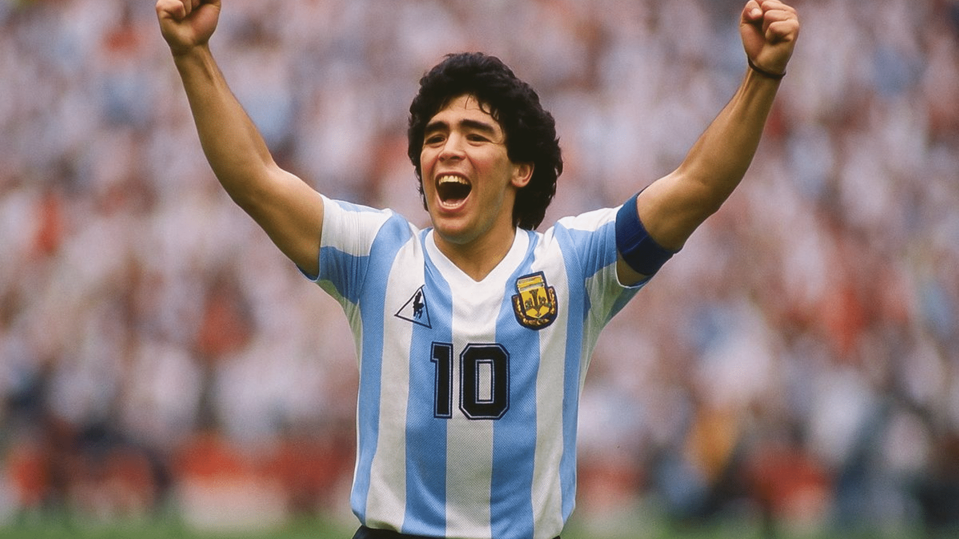 Football player celebrating with raised arms while wearing Argentina’s national team jersey on the pitch.