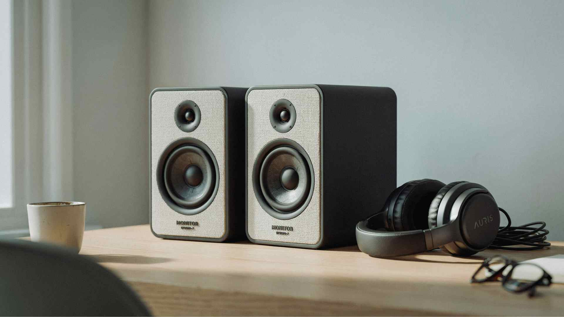 Studio monitor speakers and closed back headphones on a desk