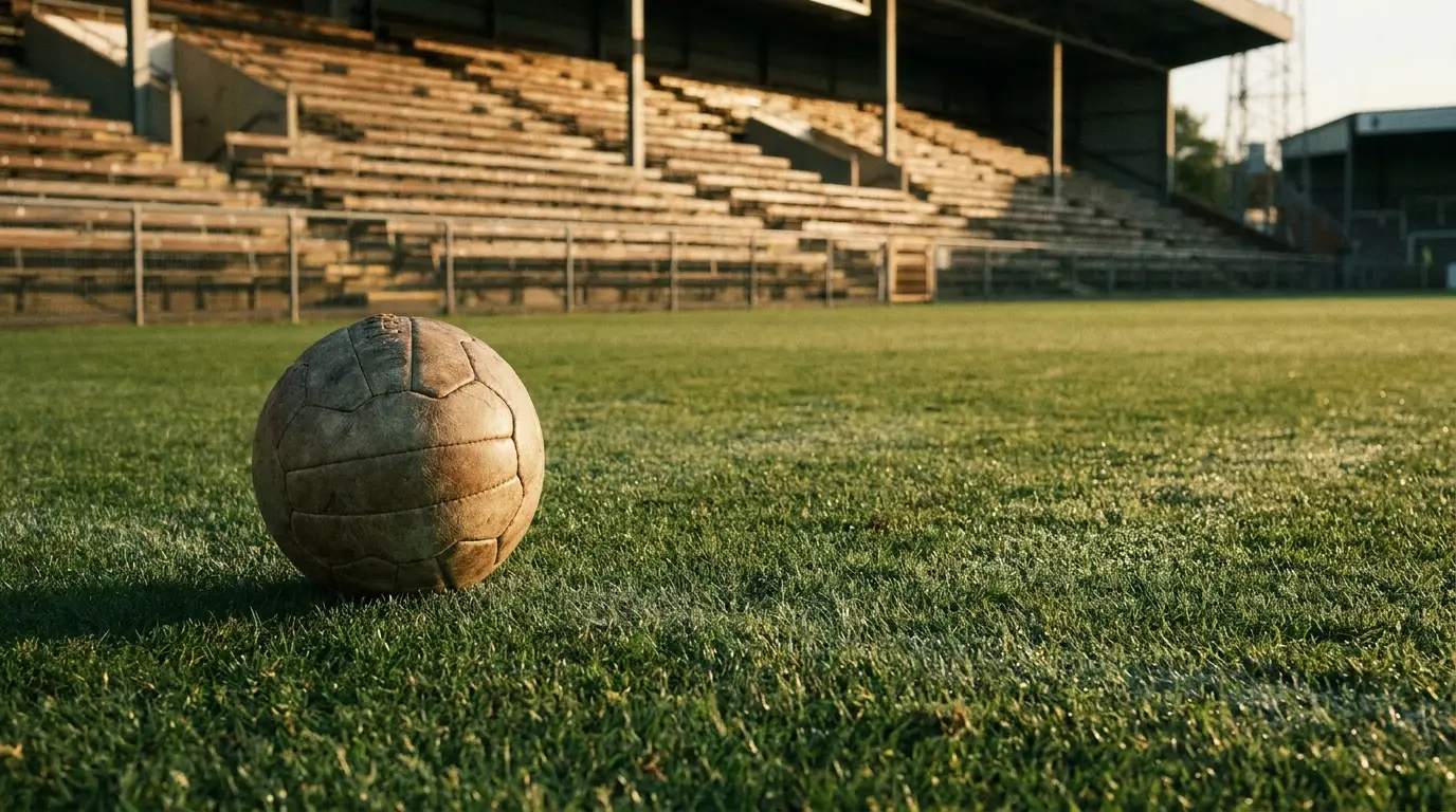 Vintage soccer ball on grassy field in front of empty stadium stands