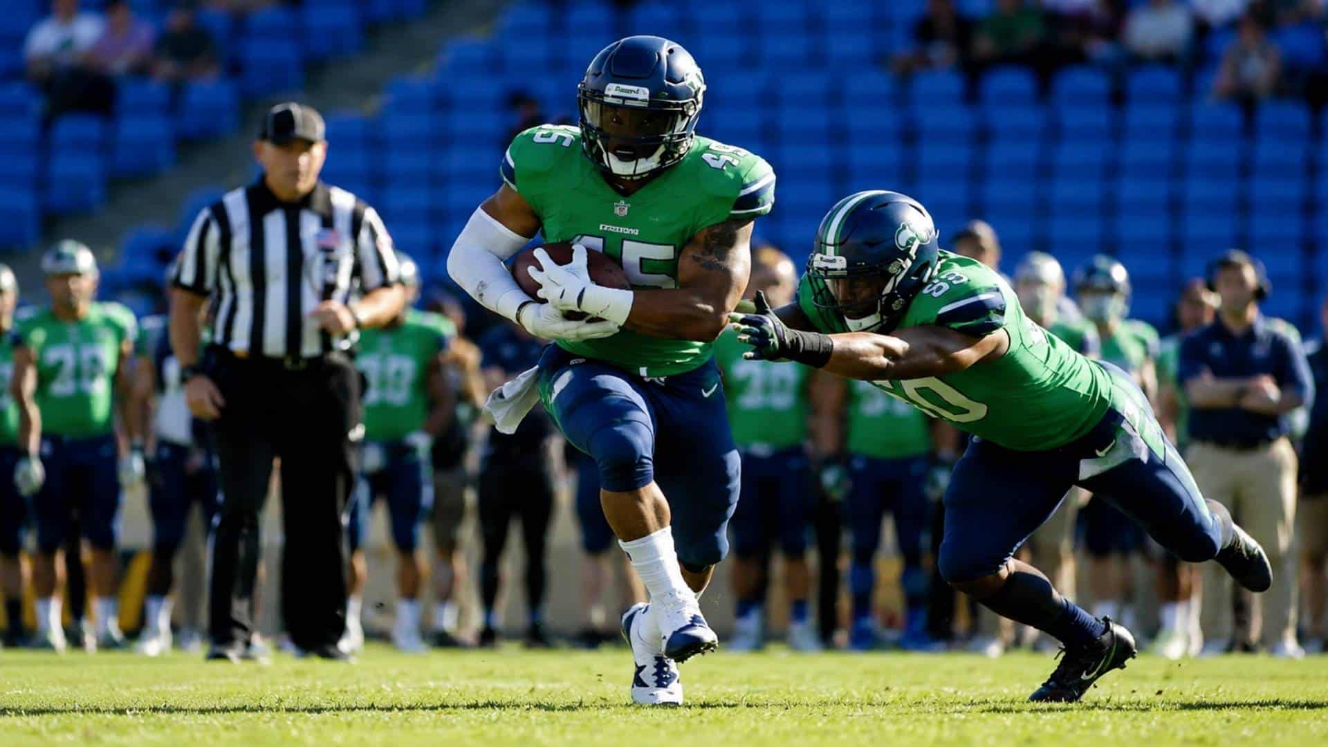 American football player in green jersey running with ball as defender in green lunges for tackle