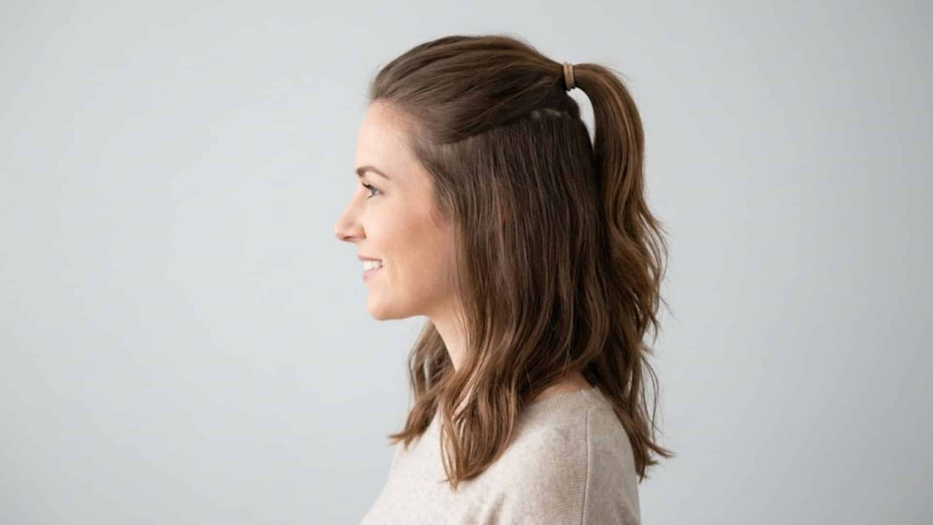 Woman with wavy brown hair in a half-up ponytail, smiling in profile