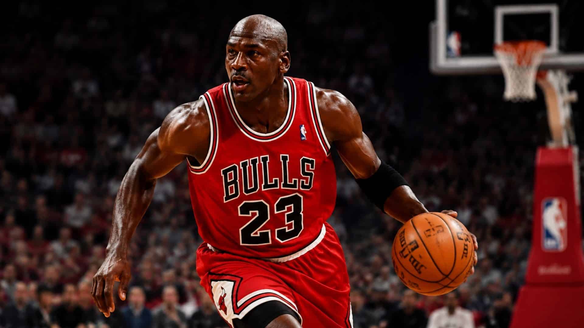 Michael Jordan in Chicago Bulls jersey dribbling the basketball during an NBA game with crowd blurred in background.