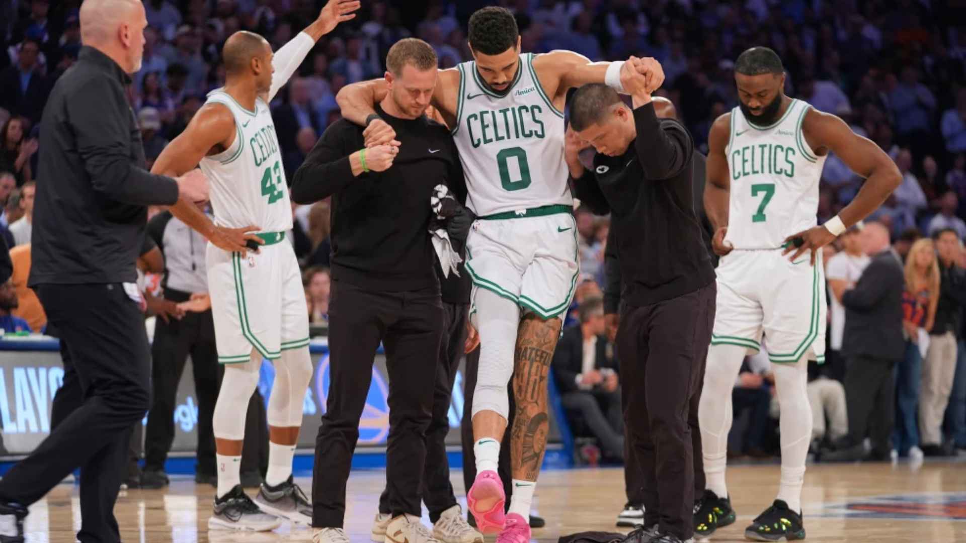 Boston Celtics players and staff help Jayson Tatum off the court during an NBA game after a lower leg injury