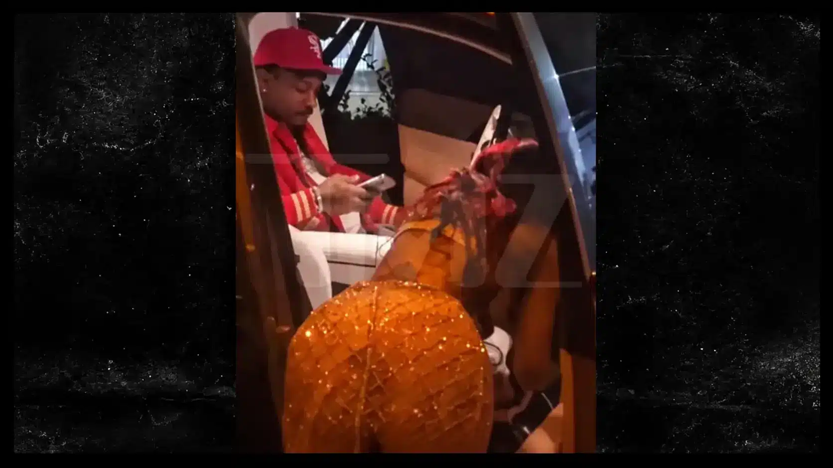 Cardi B and Stefon Diggs sitting together inside a vehicle, both wearing red caps, in a candid moment.