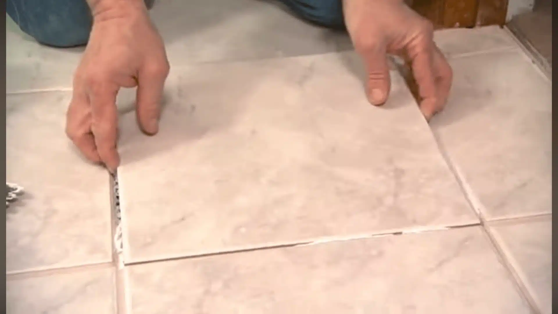 Placing a replacement tile into the floor opening and aligning it with nearby tiles.