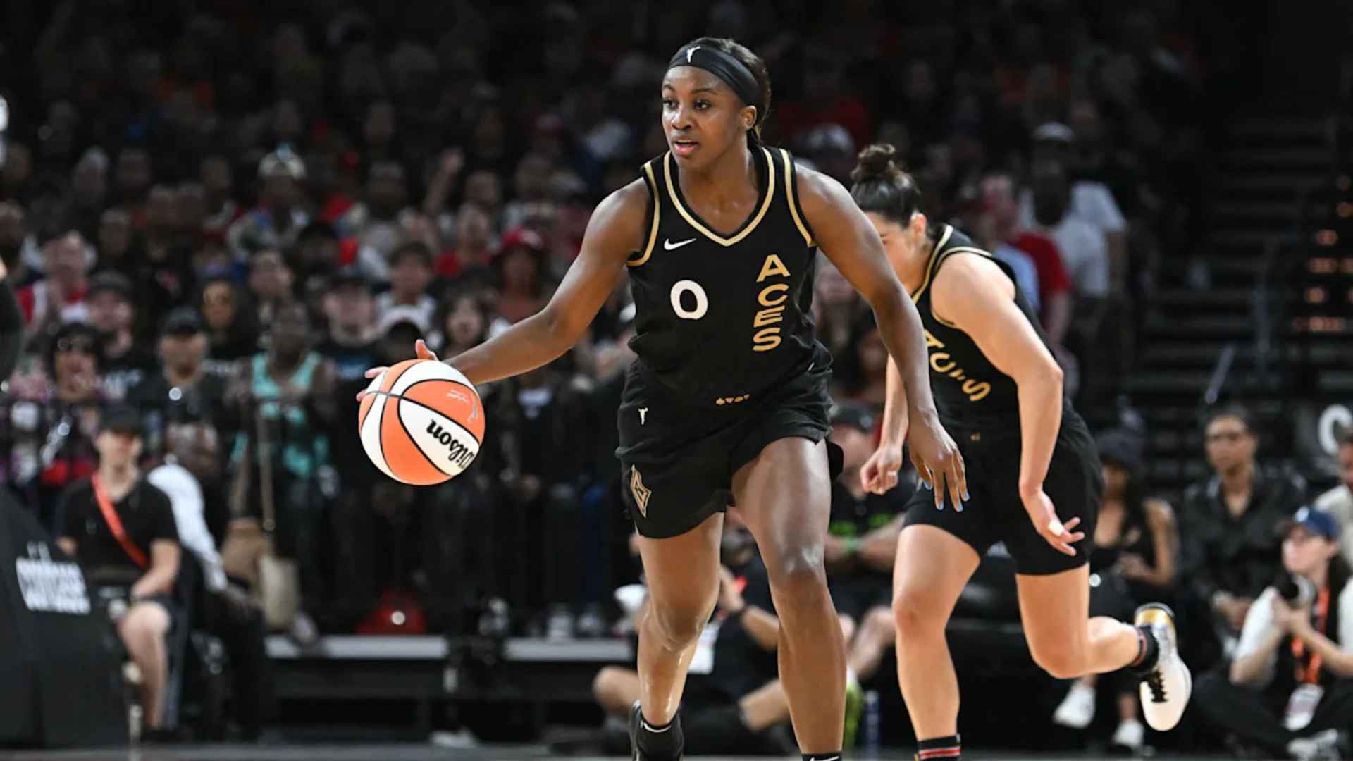 Jackie Young of the Las Vegas Aces dribbling the ball during a game in front of a crowd.