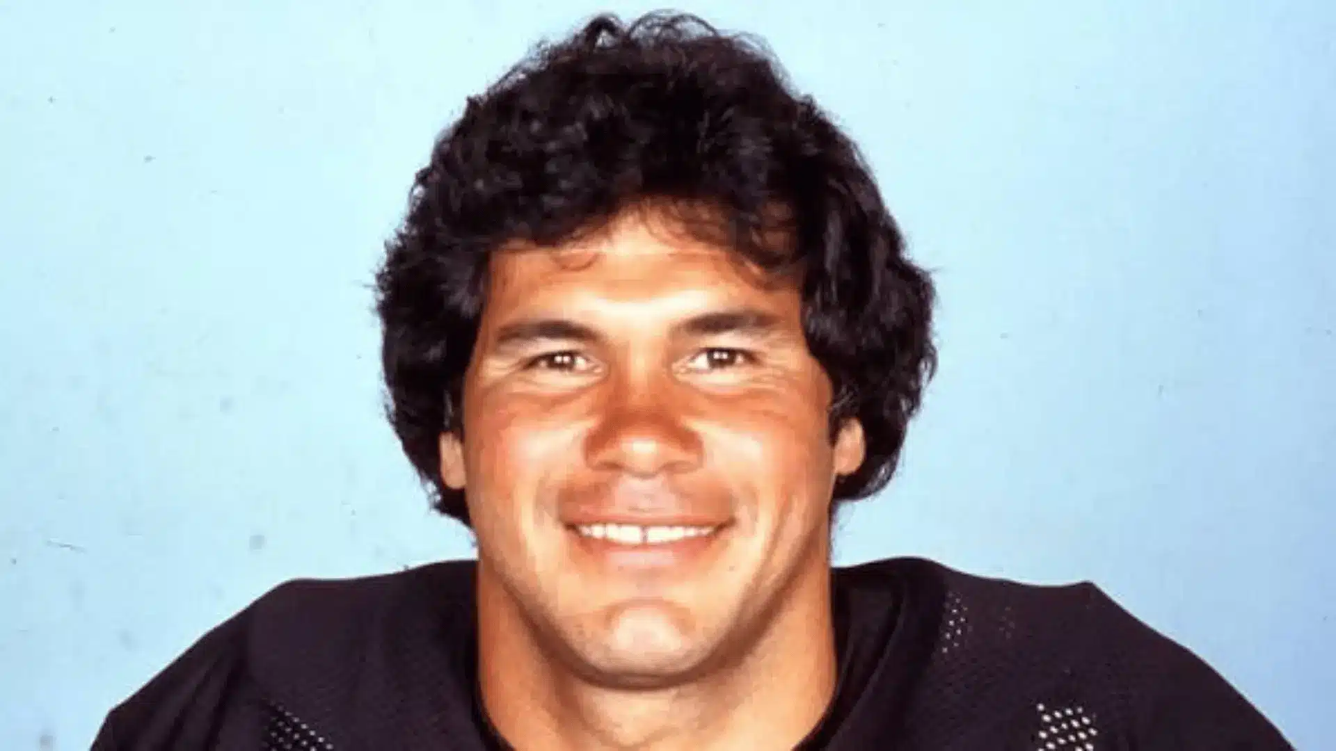 Person wearing a black sports jersey with curly hair in a portrait photo