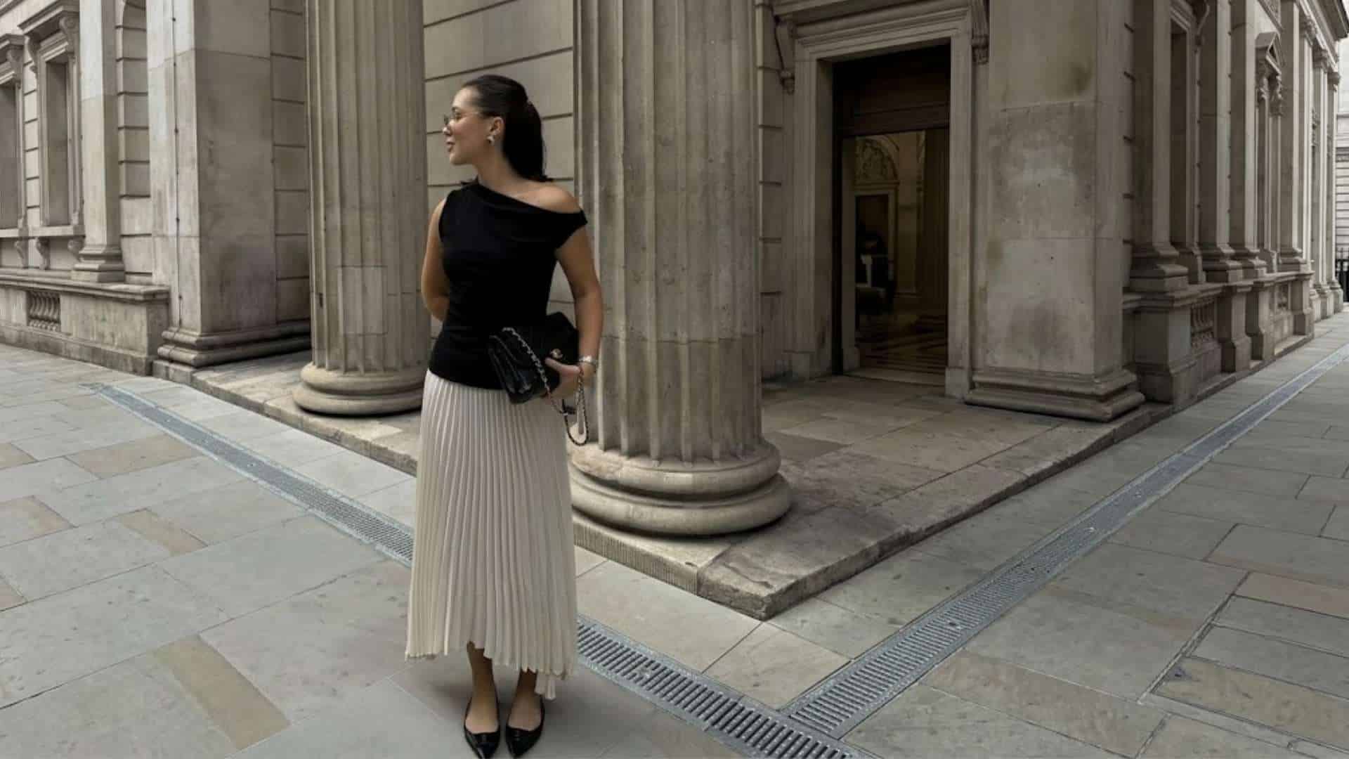 Woman wearing a black knit top with pleated midi skirt and low heels for an elegant date outfit