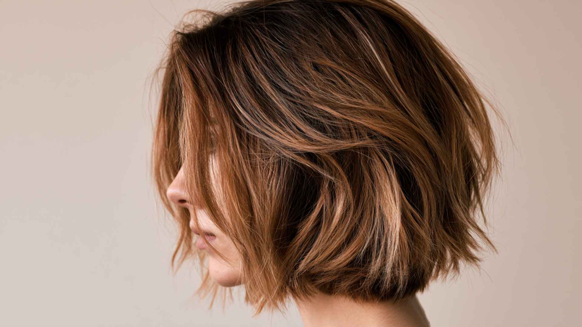 Woman with layered bob featuring dark roots fading into light ends with soft layered waves and natural transition