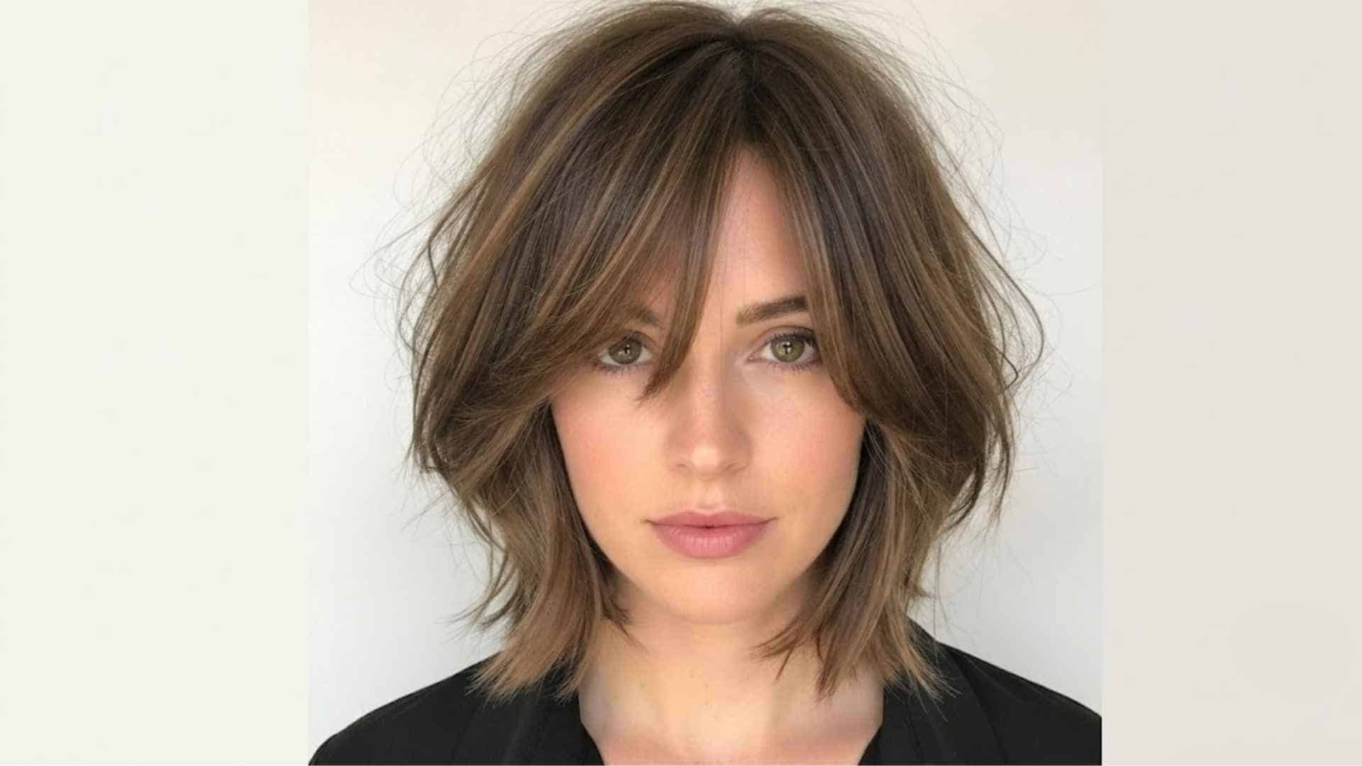 Woman with layered bob and side swept bangs blending into face framing layers with soft natural movement and shine