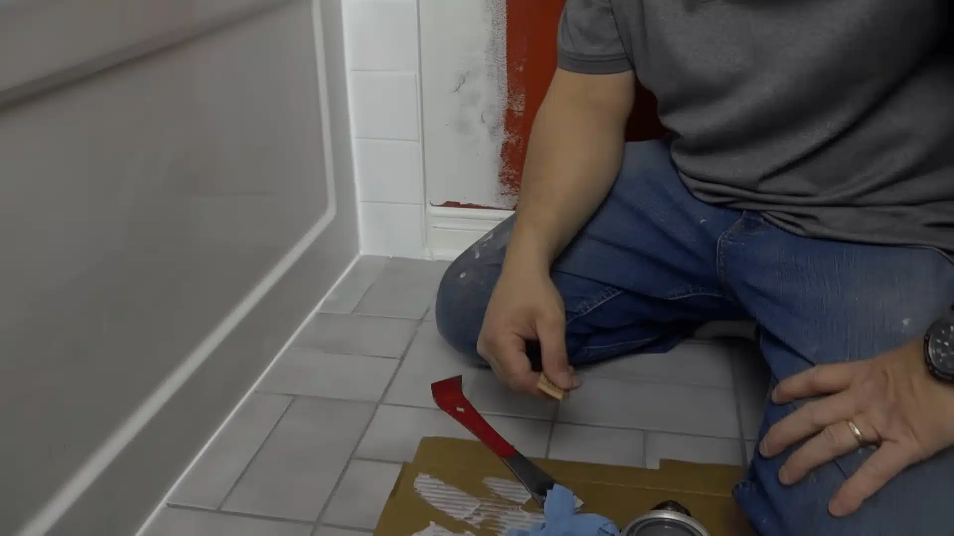 Removing excess glaze from the repaired tile edge beside the bathtub.