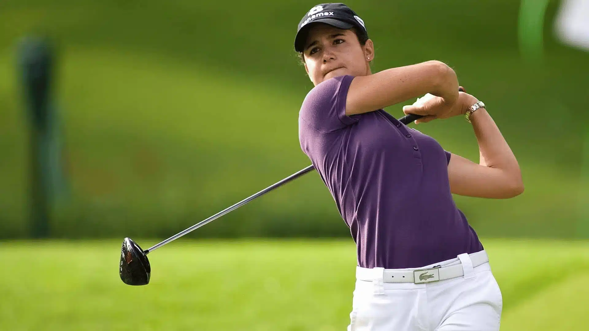 Golfer wearing a cap and polo shirt swinging a club on a golf course