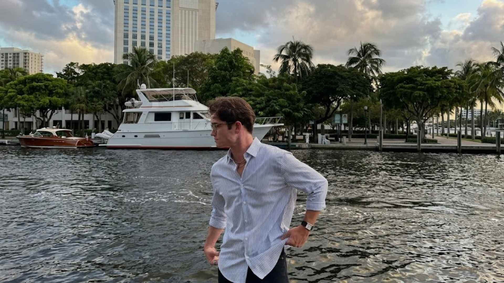 Man wearing a smart casual museum date outfit with a striped collared shirt near a waterfront city setting