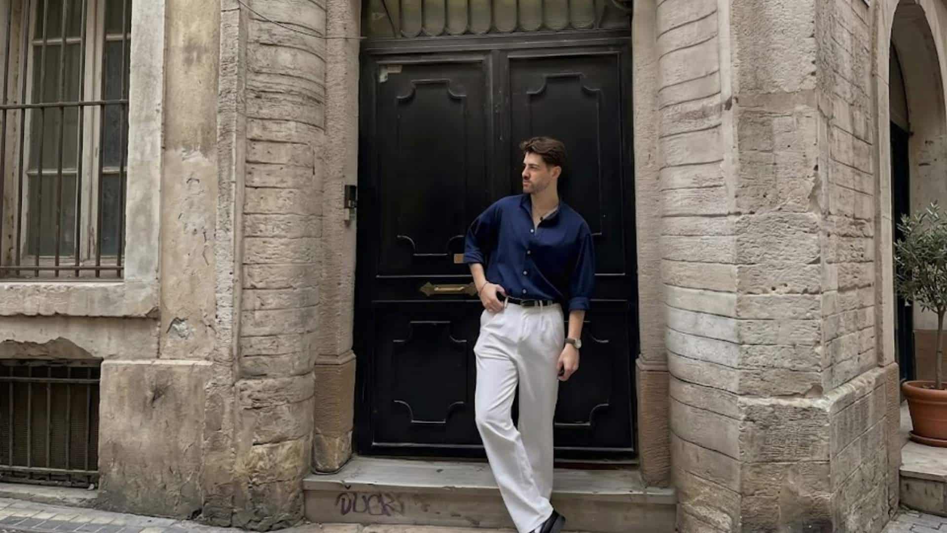 Man wearing a navy Oxford shirt with white chinos and black loafers in a classic smart casual outfit